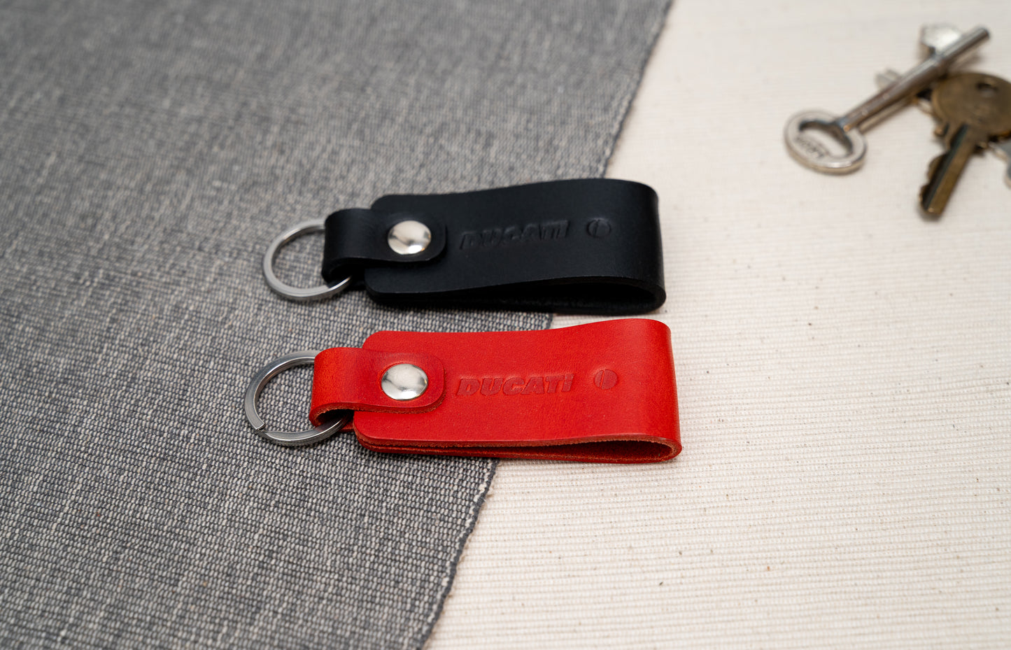 Two Ducati text logo leather keychains in black and red leather with stainless steel hardware