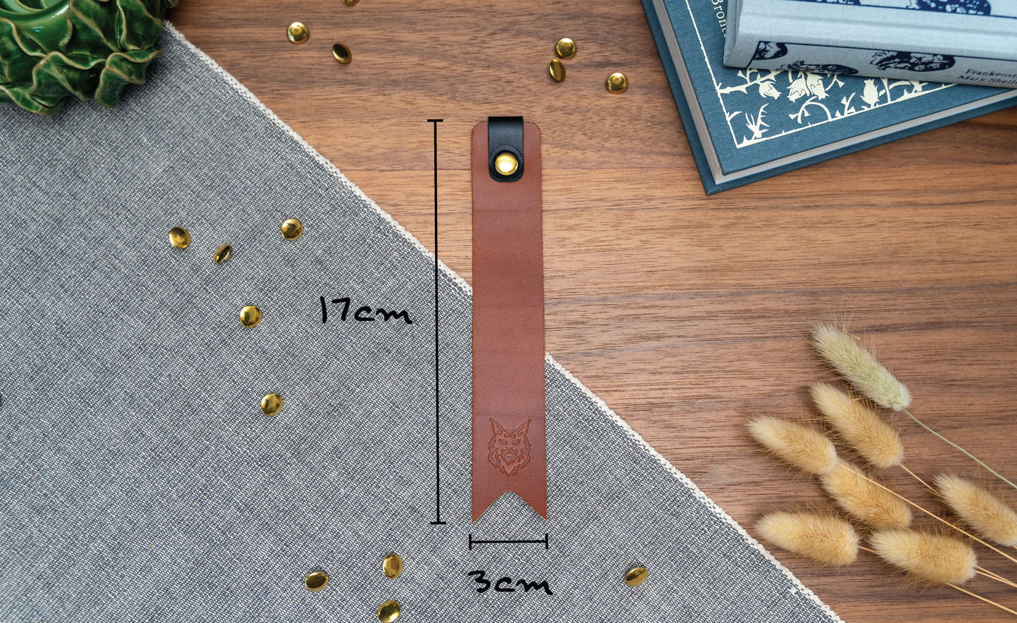 Leather bookmark in tan with a black tab folded over the top and a cut out at the bottom. Bookmark is debossed with an outline of a Maine Coon cats face. Stainless steel and brass rivets used to hold tab in place. Available in red, yellow, tan, olive green, purple, navy blue, dark brown, black with a choice of tab colour. !7cm by 3cm wide.