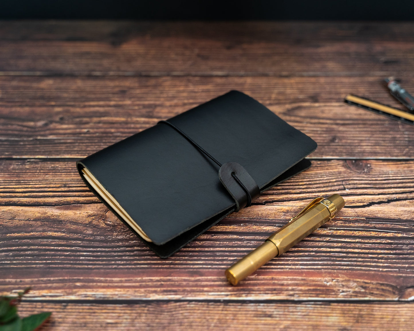 TN Passport black leather notebook cover and gold pen on a wooden surface