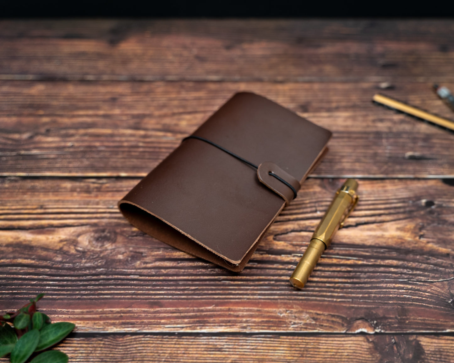 TN Passport brown leather notebook cover and gold pen on a wooden surface