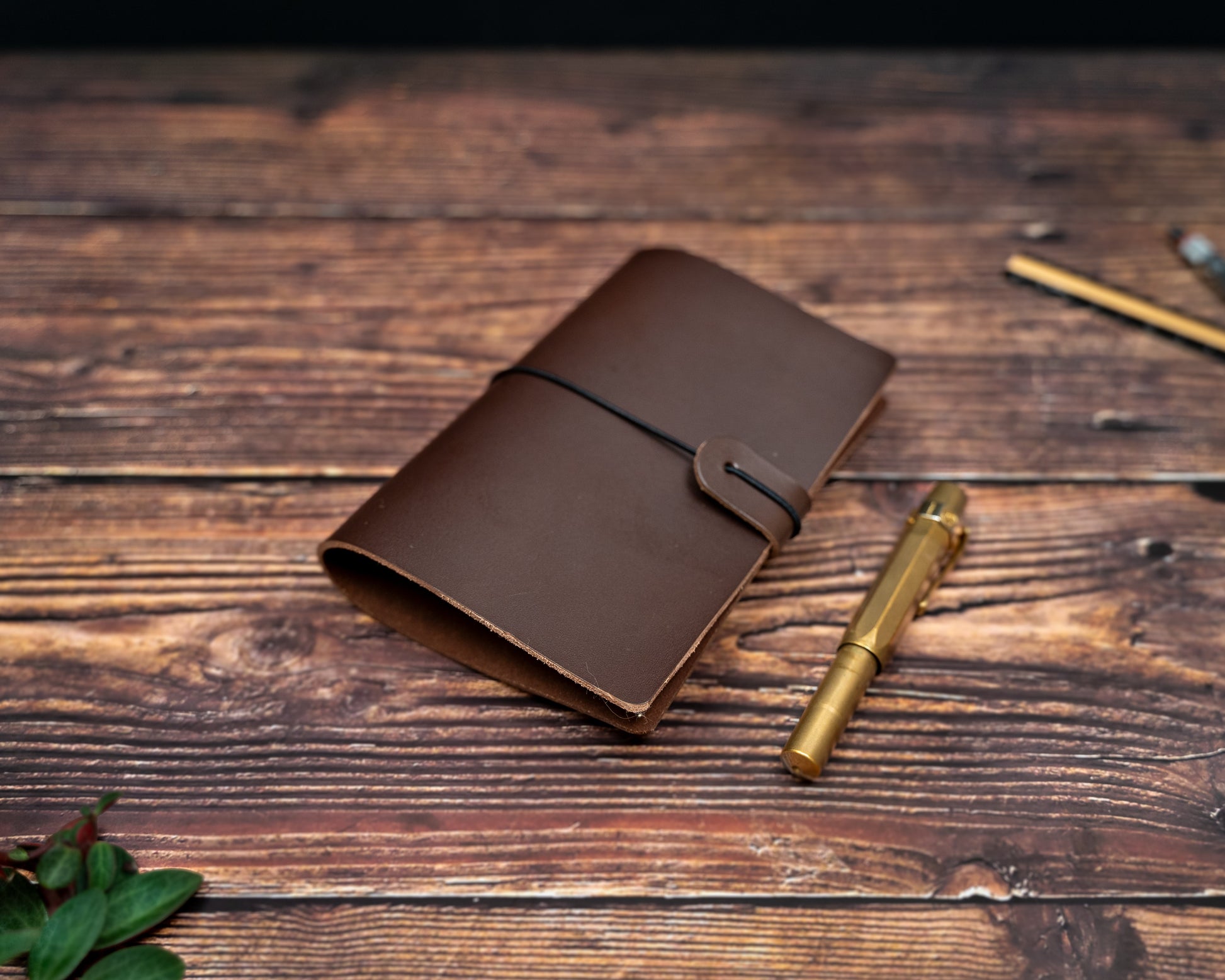 TN Passport brown leather notebook cover and gold pen on a wooden surface
