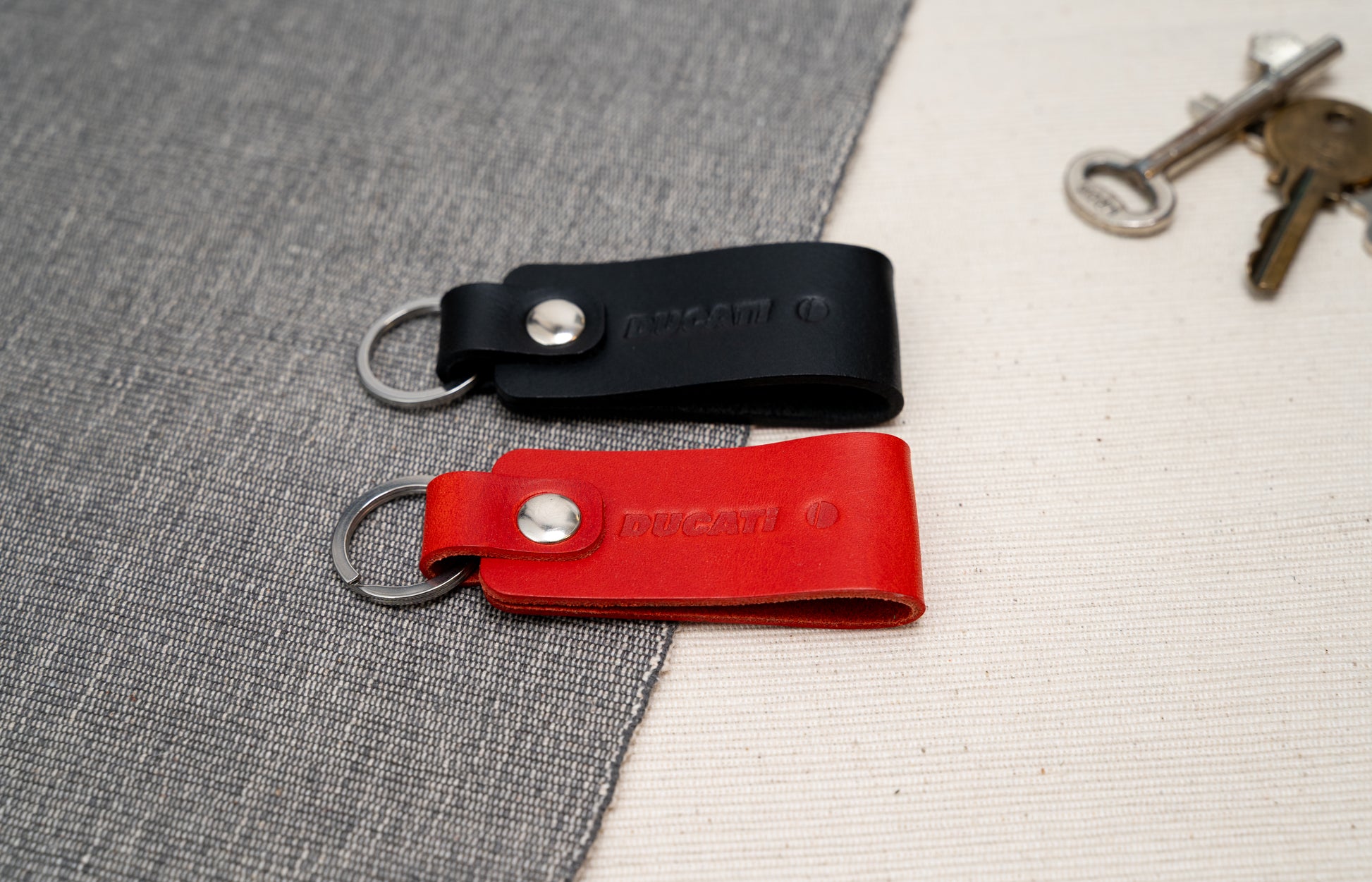 Two Ducati text logo leather keychains in black and red leather with stainless steel hardware