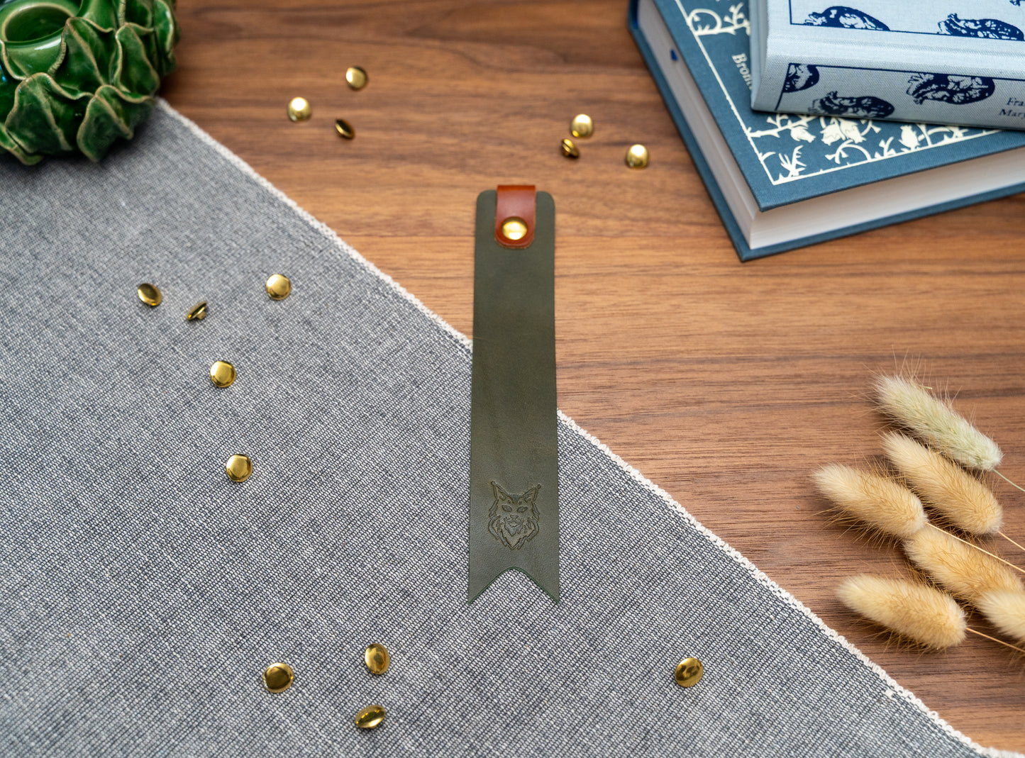 Leather bookmark in olive green with a tan tab folded over the top and a cut out at the bottom. Bookmark is debossed with an outline of a Maine Coon cats face. Stainless steel and brass rivets used to hold tab in place. Available in red, yellow, tan, olive green, purple, navy blue, dark brown, black with a choice of tab colour.