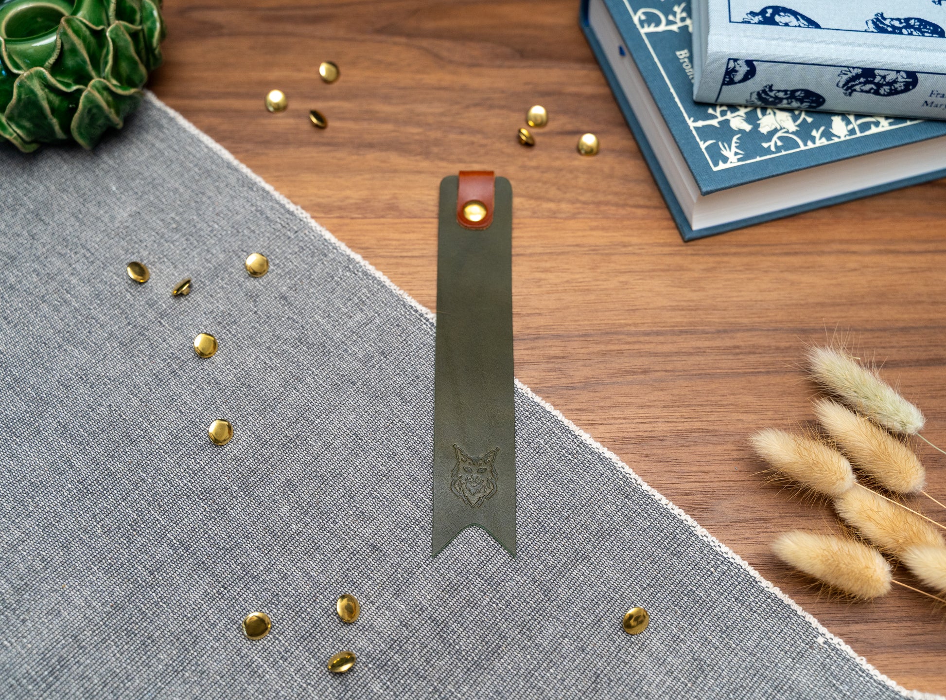 Leather bookmark in olive green with a tan tab folded over the top and a cut out at the bottom. Bookmark is debossed with an outline of a Maine Coon cats face. Stainless steel and brass rivets used to hold tab in place. Available in red, yellow, tan, olive green, purple, navy blue, dark brown, black with a choice of tab colour.