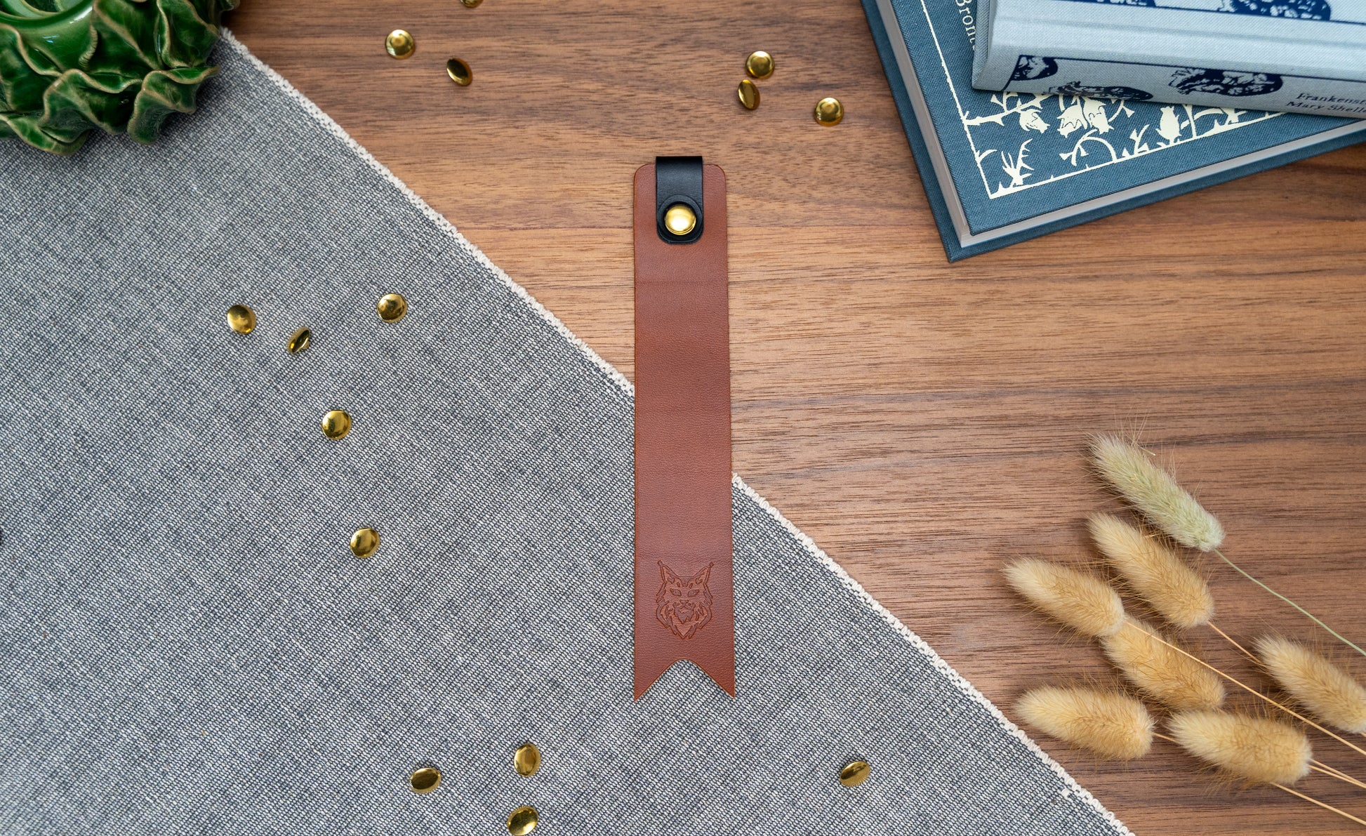 Leather bookmark in tan with a black tab folded over the top and a cut out at the bottom. Bookmark is debossed with an outline of a Maine Coon cats face. Stainless steel and brass rivets used to hold tab in place. Available in red, yellow, tan, olive green, purple, navy blue, dark brown, black with a choice of tab colour.