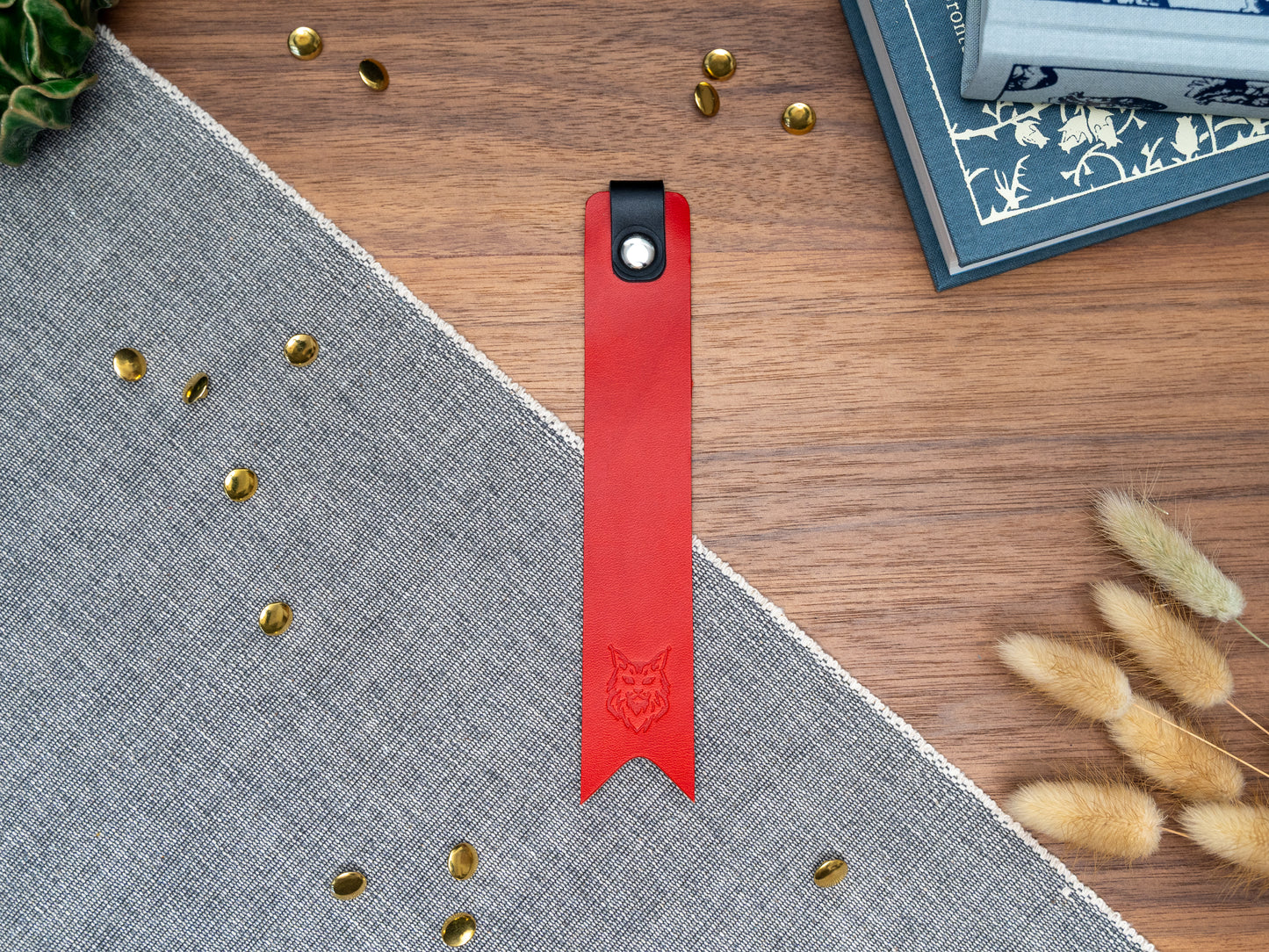 Leather bookmark in red with a black tab folded over the top and a cut out at the bottom. Bookmark is debossed with an outline of a Maine Coon cats face. Stainless steel and brass rivets used to hold tab in place. Available in red, yellow, tan, olive green, purple, navy blue, dark brown, black with a choice of tab colour.