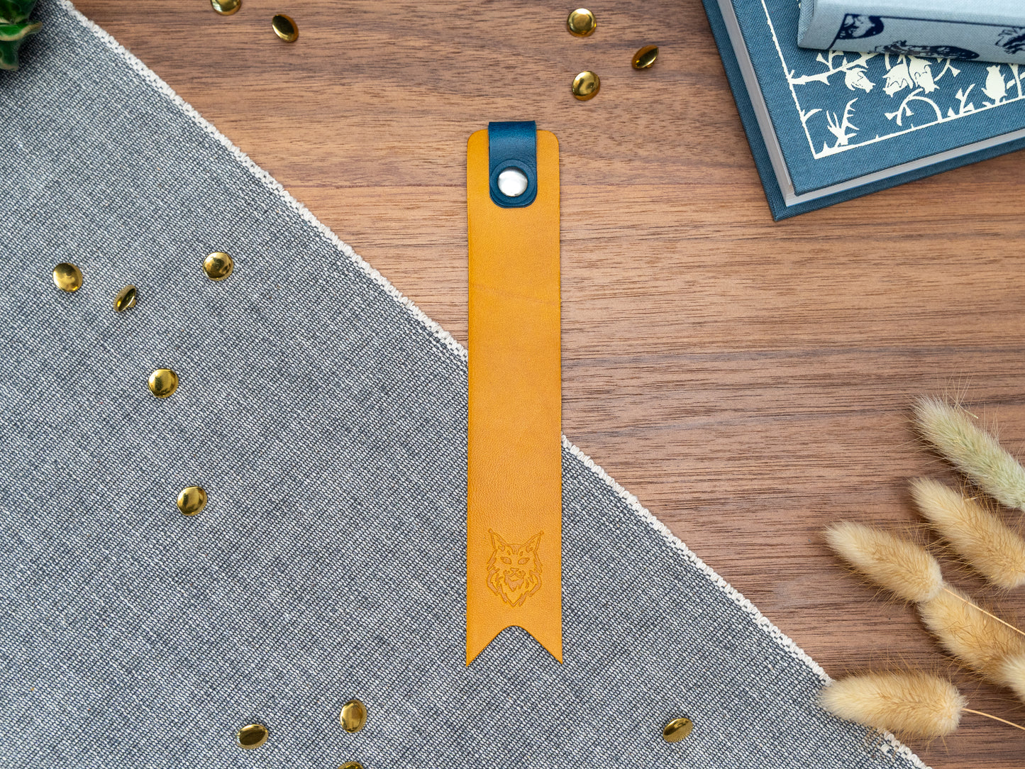 Leather bookmark in yellow with a navy blue tab folded over the top and a cut out at the bottom. Bookmark is debossed with an outline of a Maine Coon cats face. Stainless steel and brass rivets used to hold tab in place. Available in red, yellow, tan, olive green, purple, navy blue, dark brown, black with a choice of tab colour.