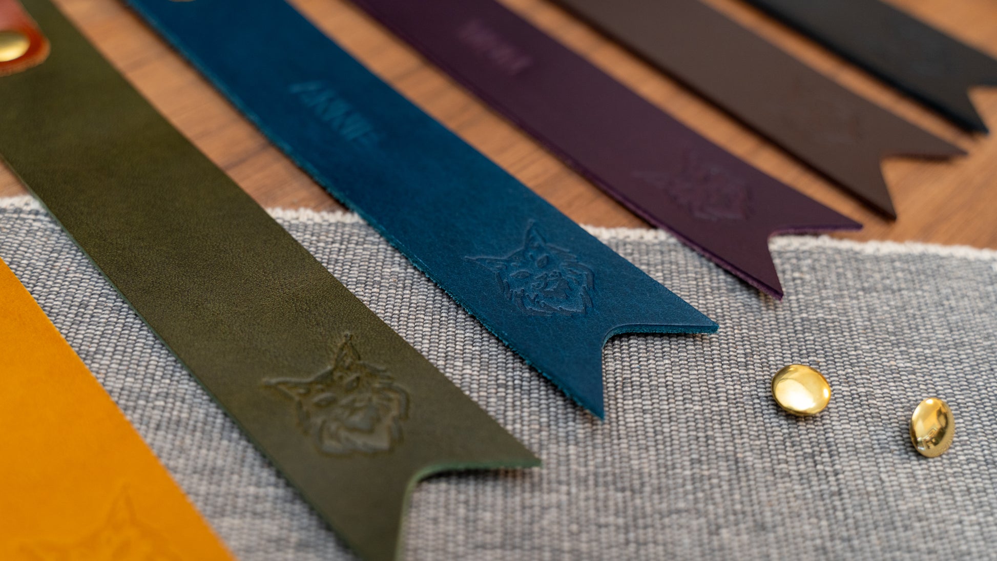 Leather bookmark in a selection of colours with folded tab over the top and a cut out at the bottom. Bookmark is debossed with an outline of a Maine Coon cats face. Stainless steel and brass rivets used to hold tab in place. Available in red, yellow, tan, olive green, purple, navy blue, dark brown, black with a choice of tab colour.