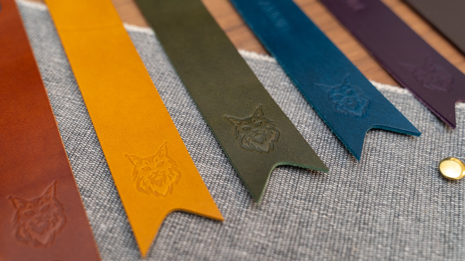 Leather bookmark in a selection of colours with folder tab over the top and a cut out at the bottom. Bookmark is debossed with an outline of a Maine Coon cats face. Stainless steel and brass rivets used to hold tab in place. Available in red, yellow, tan, olive green, purple, navy blue, dark brown, black with a choice of tab colour.
