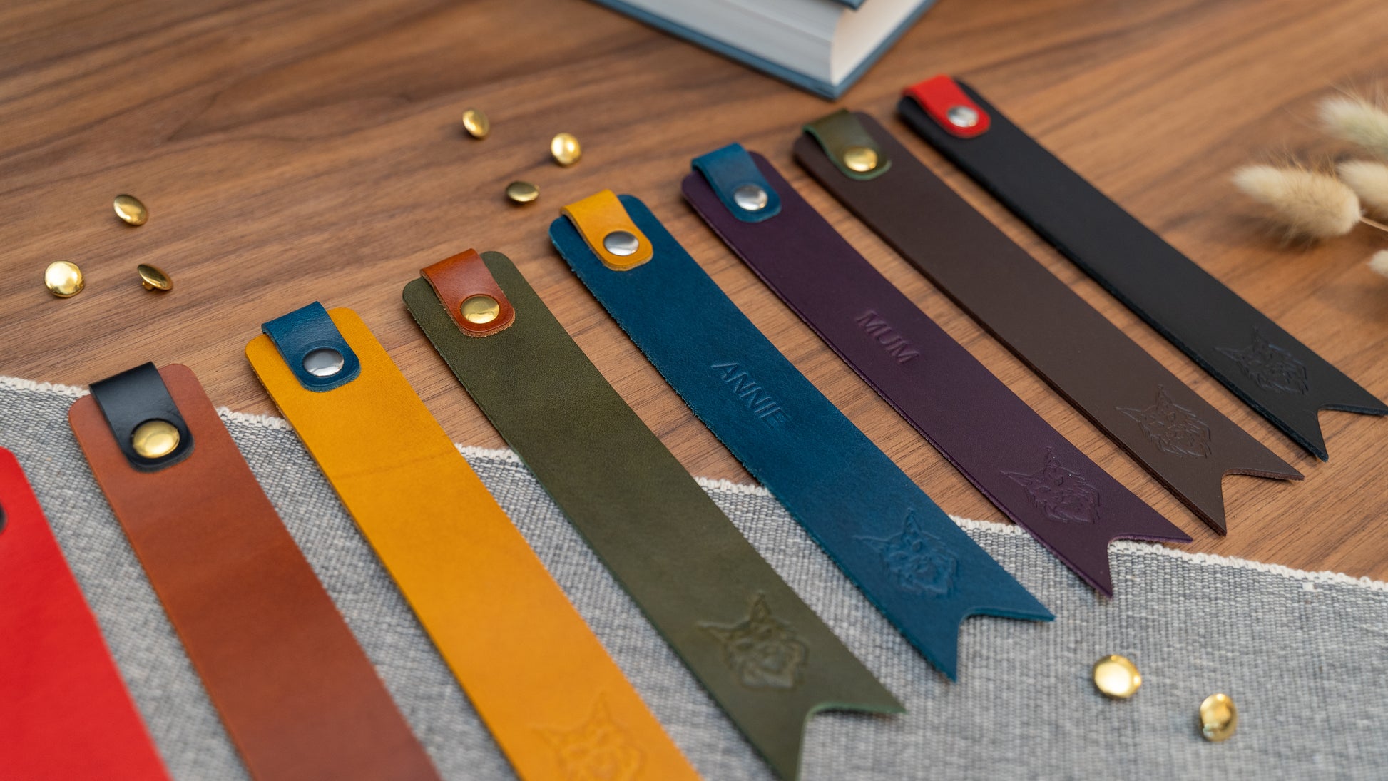 Leather bookmark in a selection of colours with folder tab over the top and a cut out at the bottom. Bookmark is debossed with an outline of a Maine Coon cats face. Stainless steel and brass rivets used to hold tab in place. Available in red, yellow, tan, olive green, purple, navy blue, dark brown, black with a choice of tab colour.