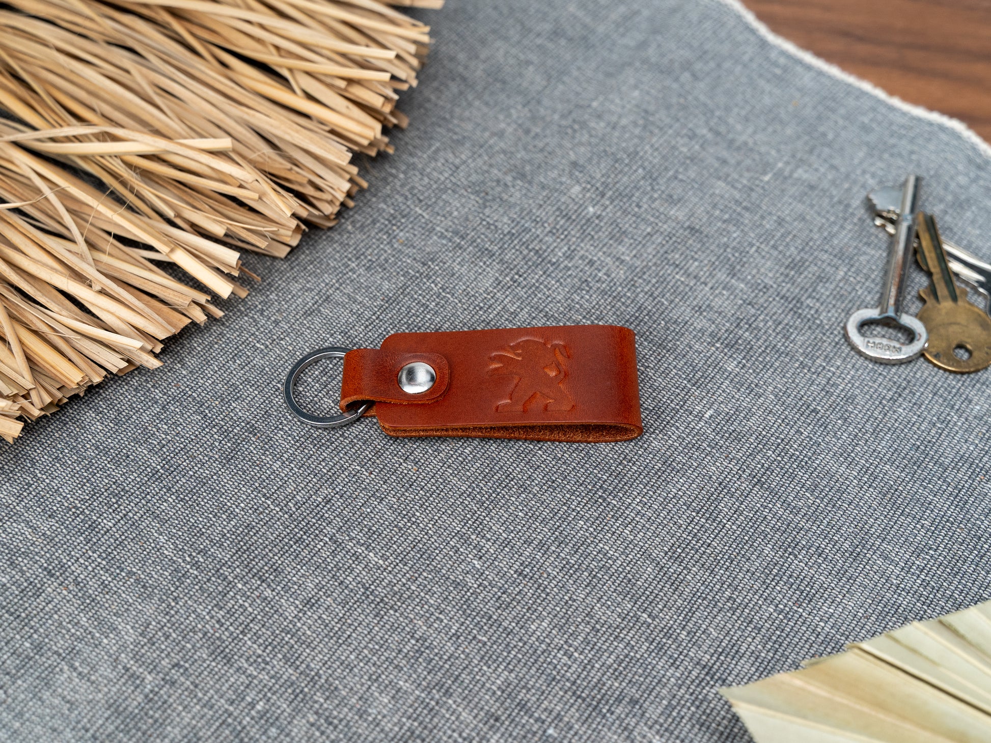 Folded tan leather keyring with the Peugeot car logo debossed on it. Made from Italian full grain leather