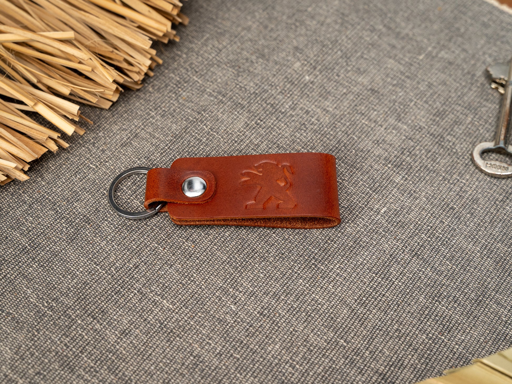 Folded tan leather keyring/keychain with the Peugeot car logo debossed on it. Made from full grain leather.