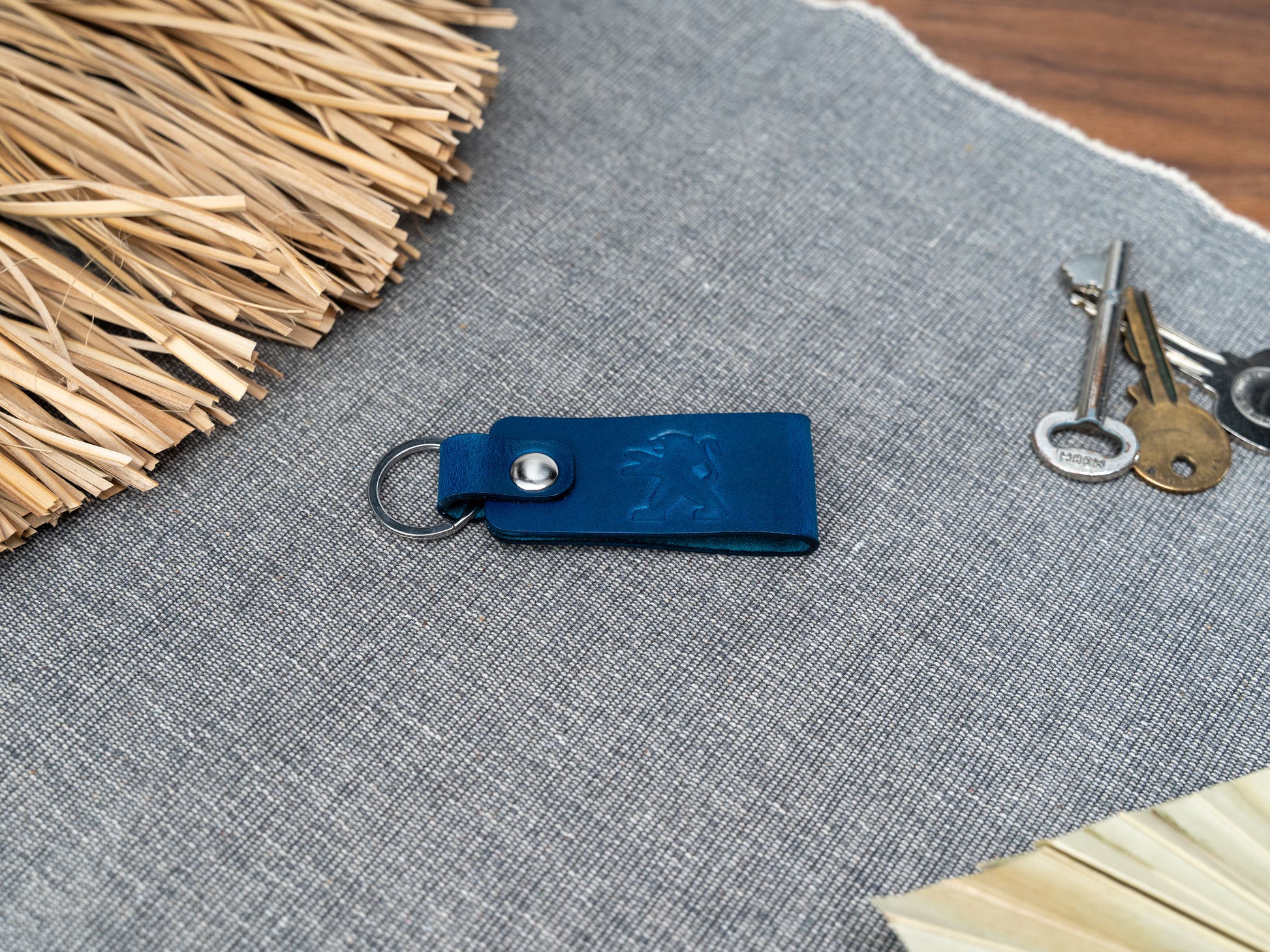 Folded navy blue leather keyring with the Peugeot car logo debossed on it. Made from Italian full grain leather