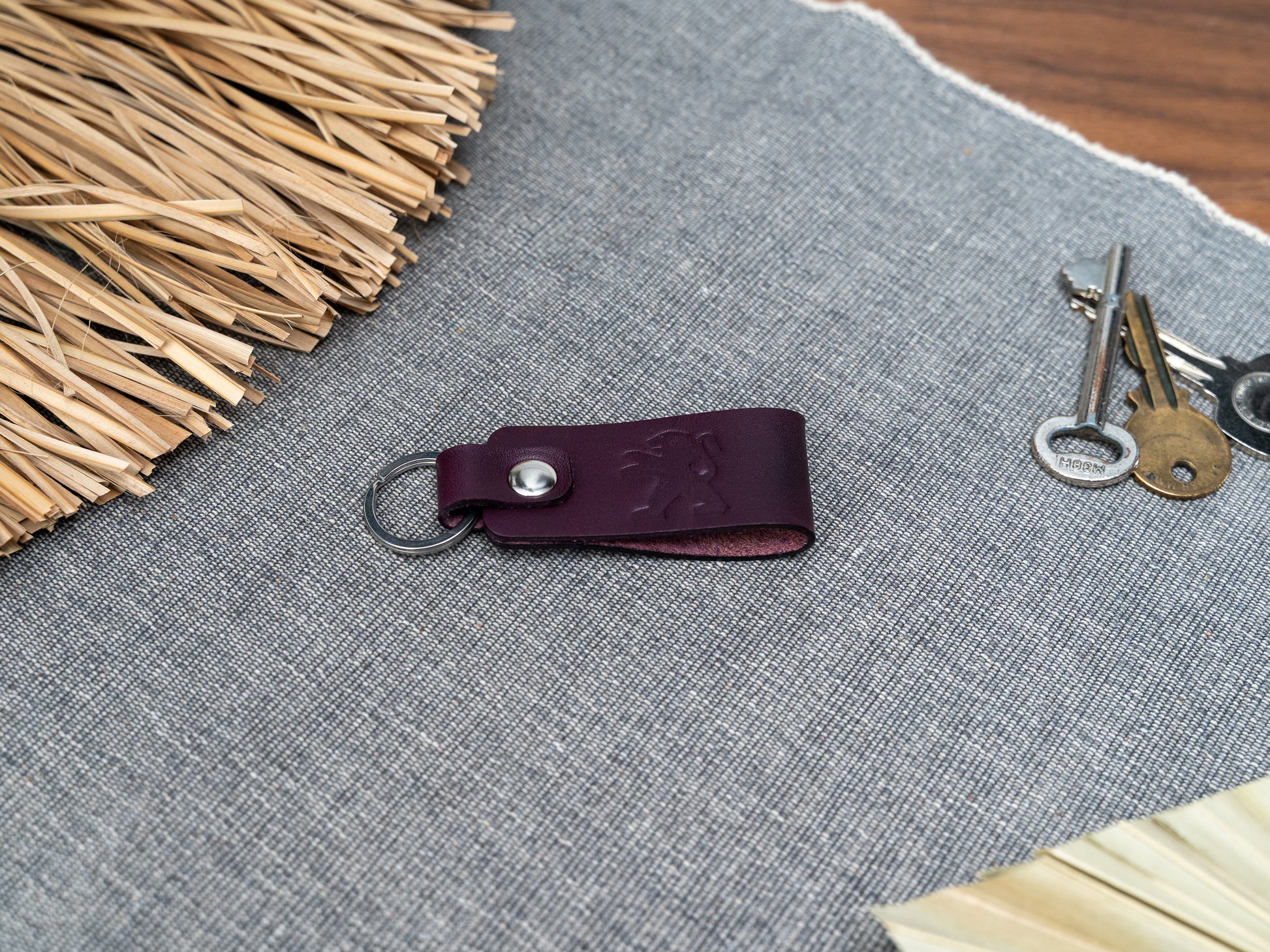 Folded purple leather keyring with the Peugeot car logo debossed on it. Made from Italian full grain leather