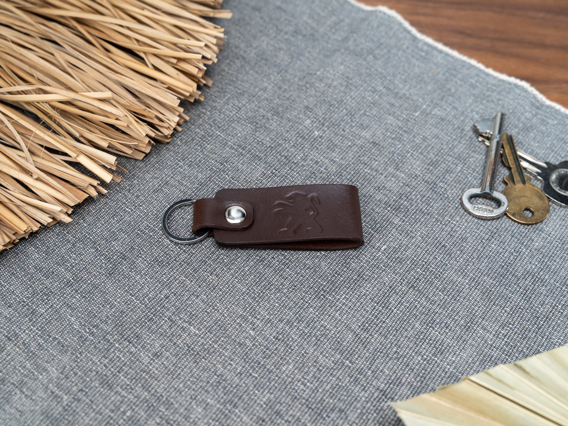 Folded dark brown leather keyring with the Peugeot car logo debossed on it. Made from full grain leather