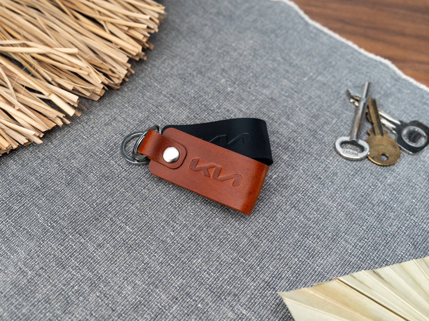 Folded tan and black leather keyrings with kia car logo debossed on them