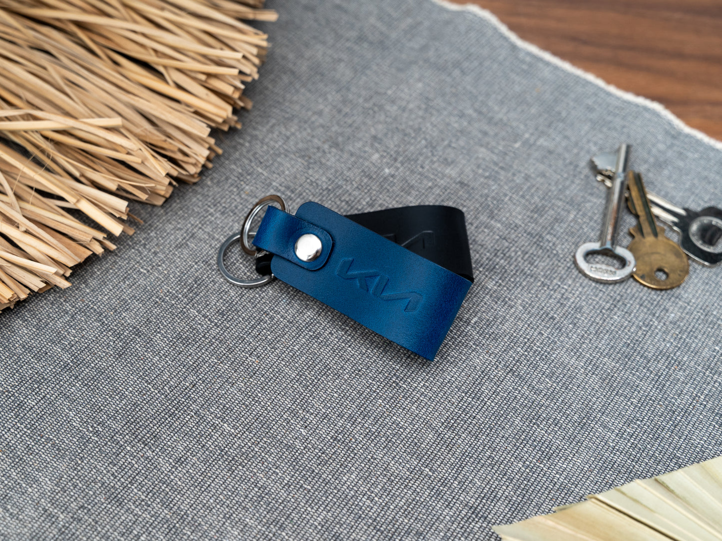 Folded blue and black leather keyrings with kia car logo debossed on them