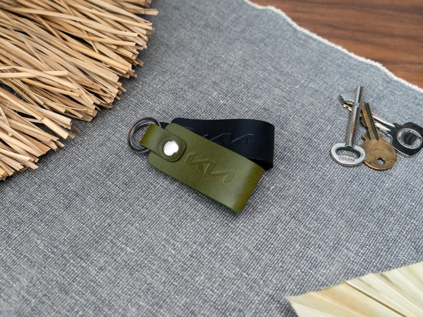 Folded olive green and black leather keyrings with kia car logo debossed on them