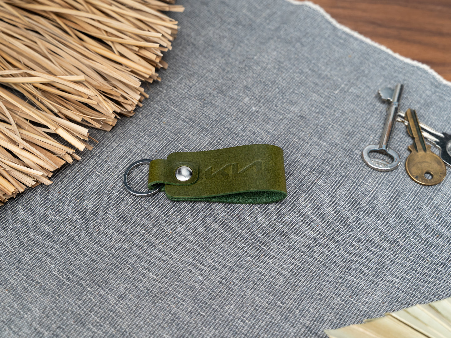 Folded olive green leather keyring with kia car logo debossed on it