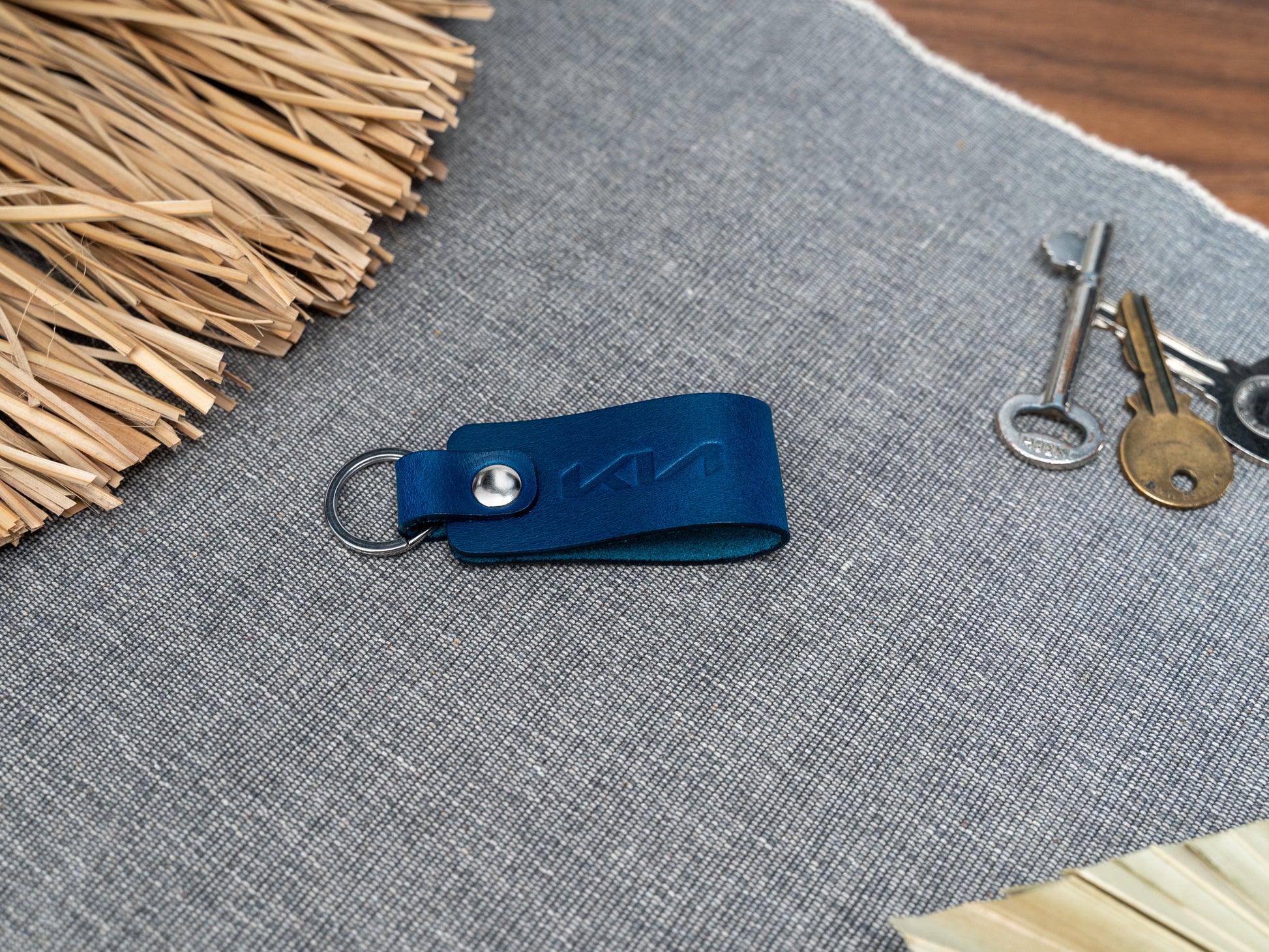 Folded navy blue leather keyring with kia car logo debossed on it