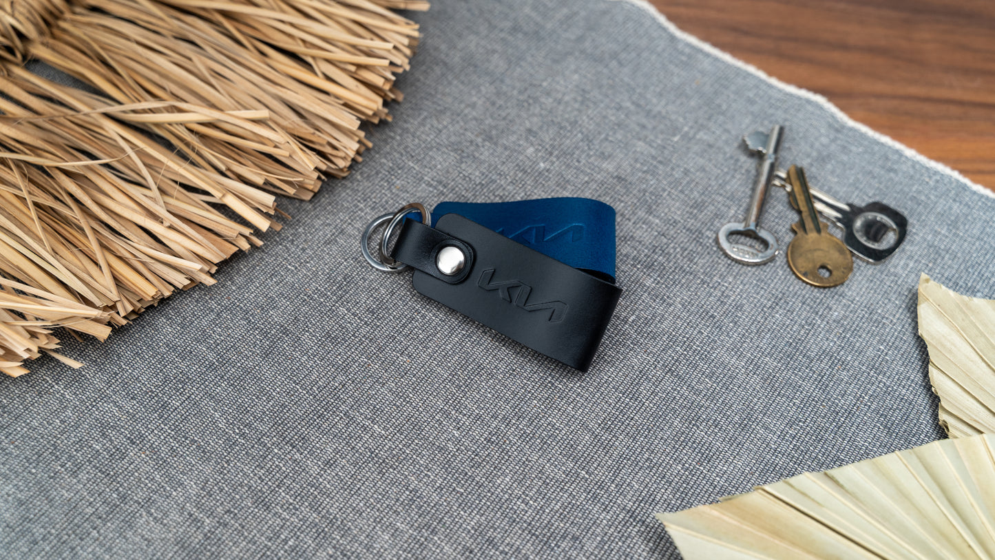 Folded navy blue and black leather keyrings with kia car logo debossed on them. Made from Italian full grain leather