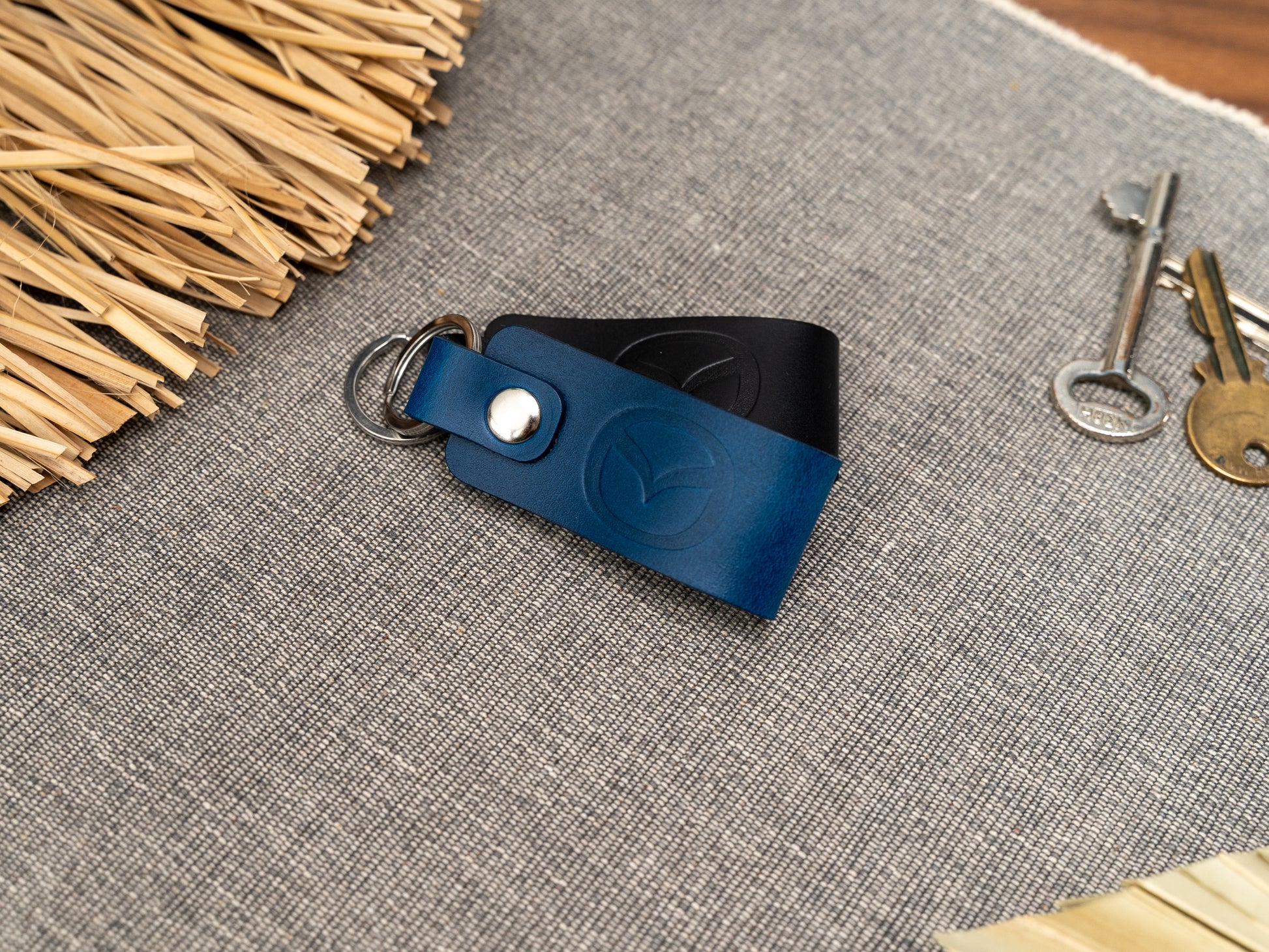 Folded navy blue and black leather keyrings/keychains with the Mazda car logo debossed on them. Made from full grain leather with stainless steel split ring and rivet.