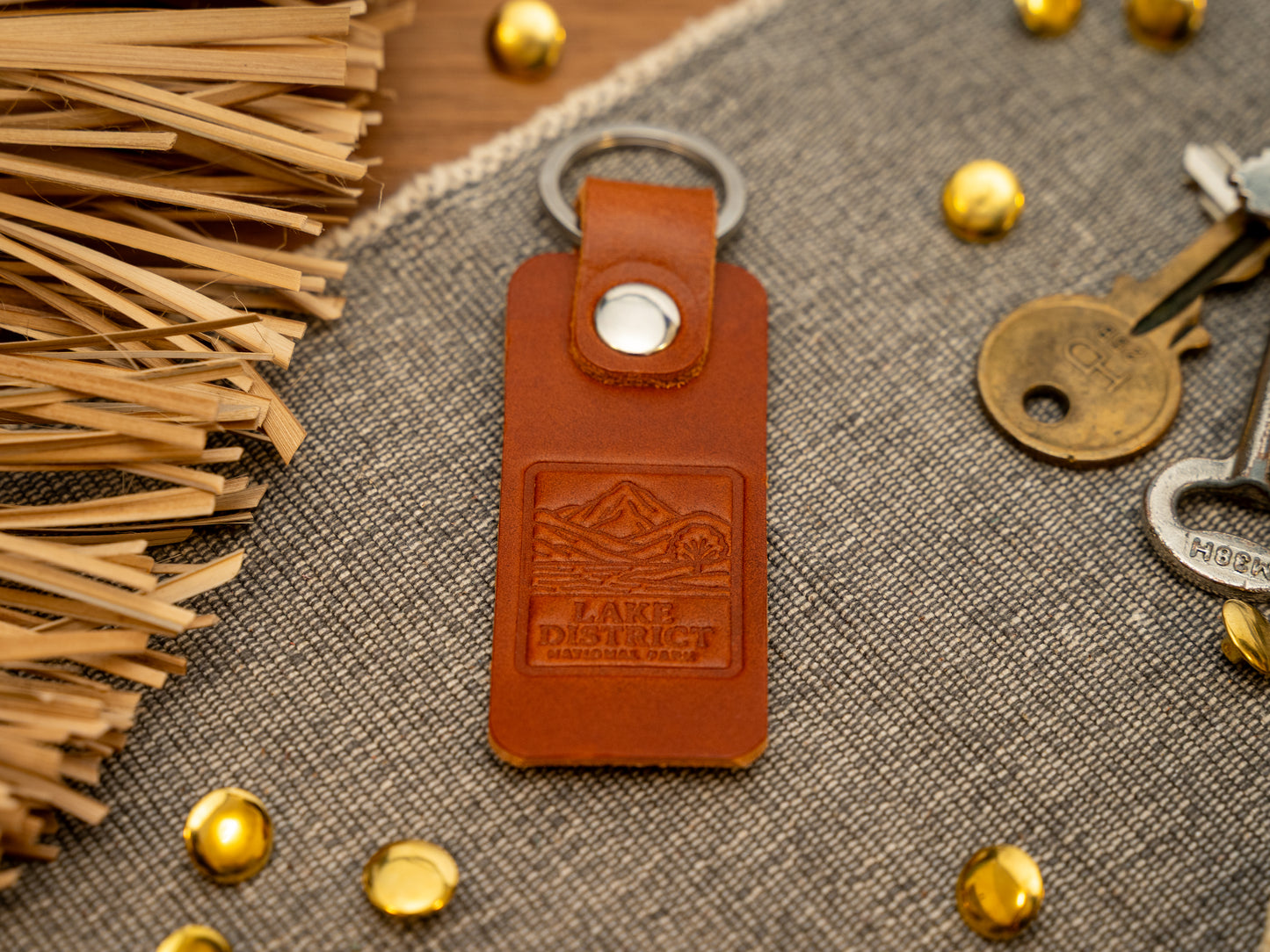 A leather keyring with a rectangular design in tan. Keyring/keychain is debossed with an image of the lake district. Stainless steel split ring and rivet.