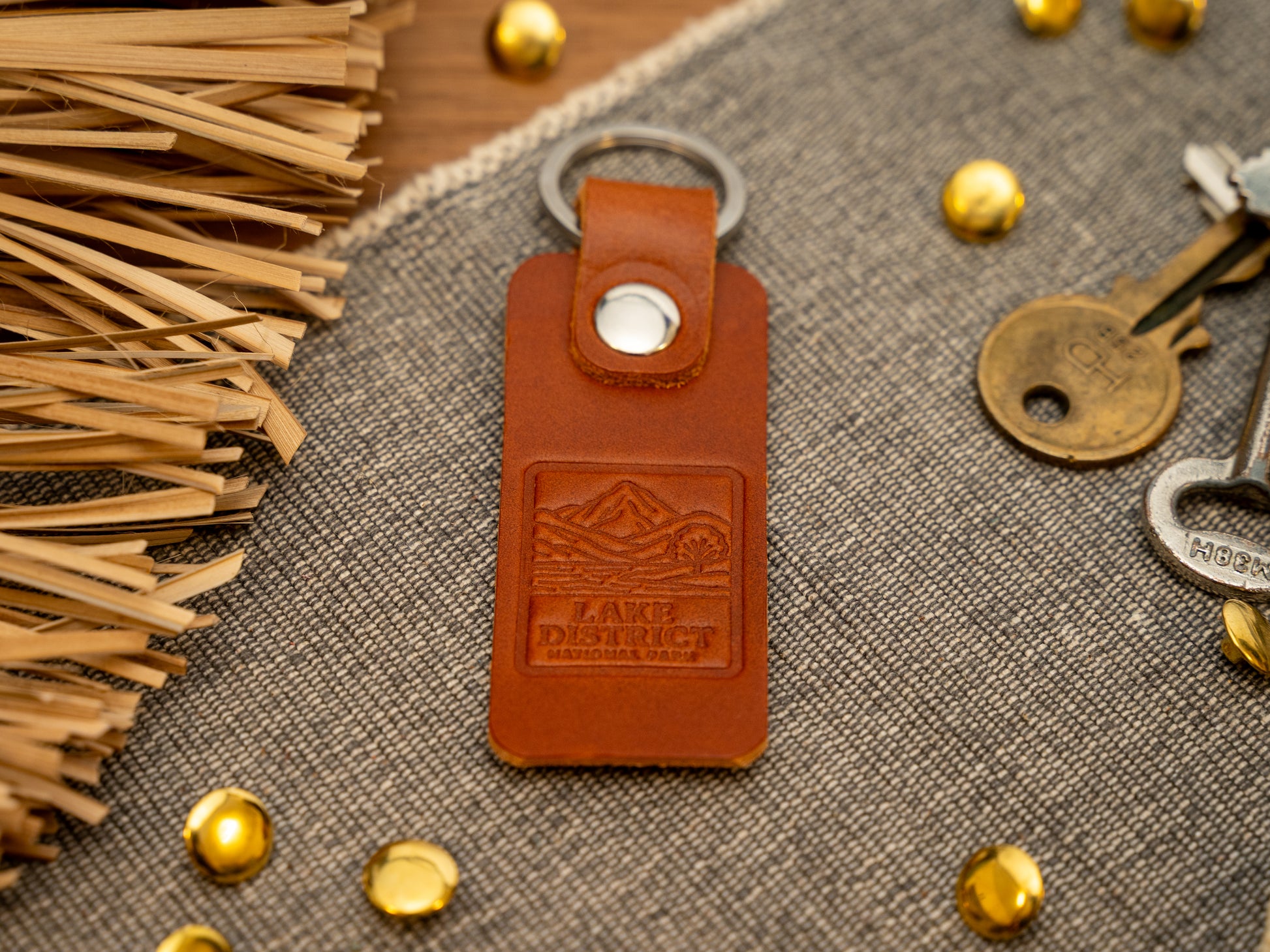 A leather keyring with a rectangular design in tan. Keyring/keychain is debossed with an image of the lake district. Stainless steel split ring and rivet.