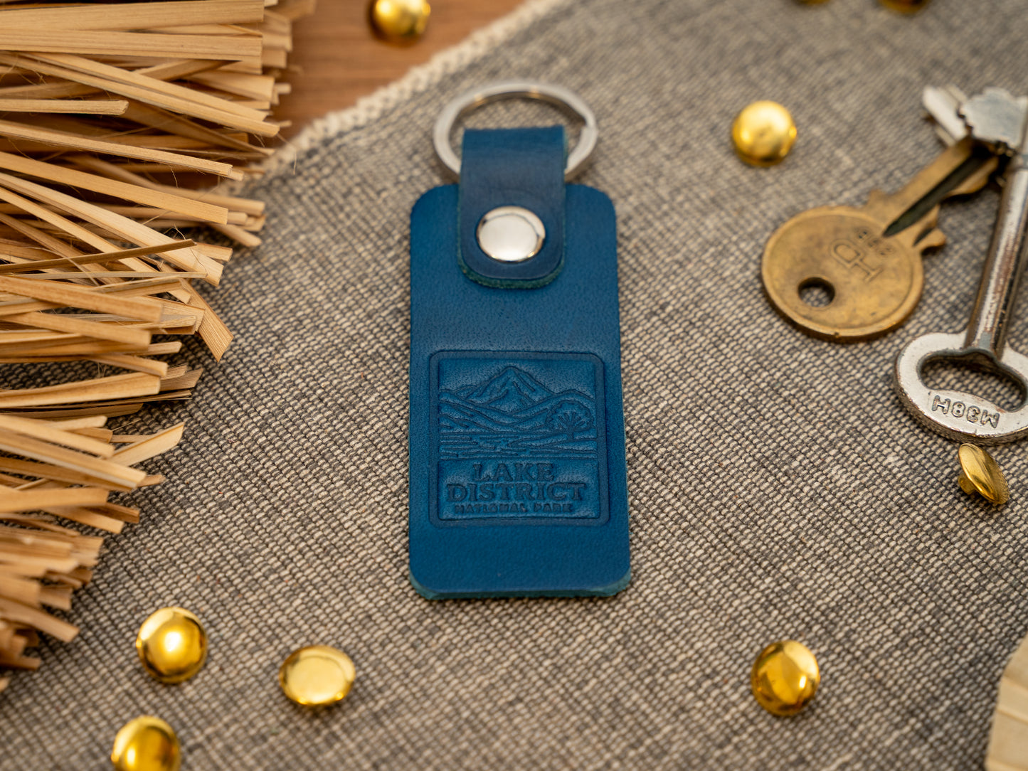 A leather keyring with a rectangular design in navy blue. Keyring/keychain is debossed with an image of the lake district. Stainless steel split ring and rivet.