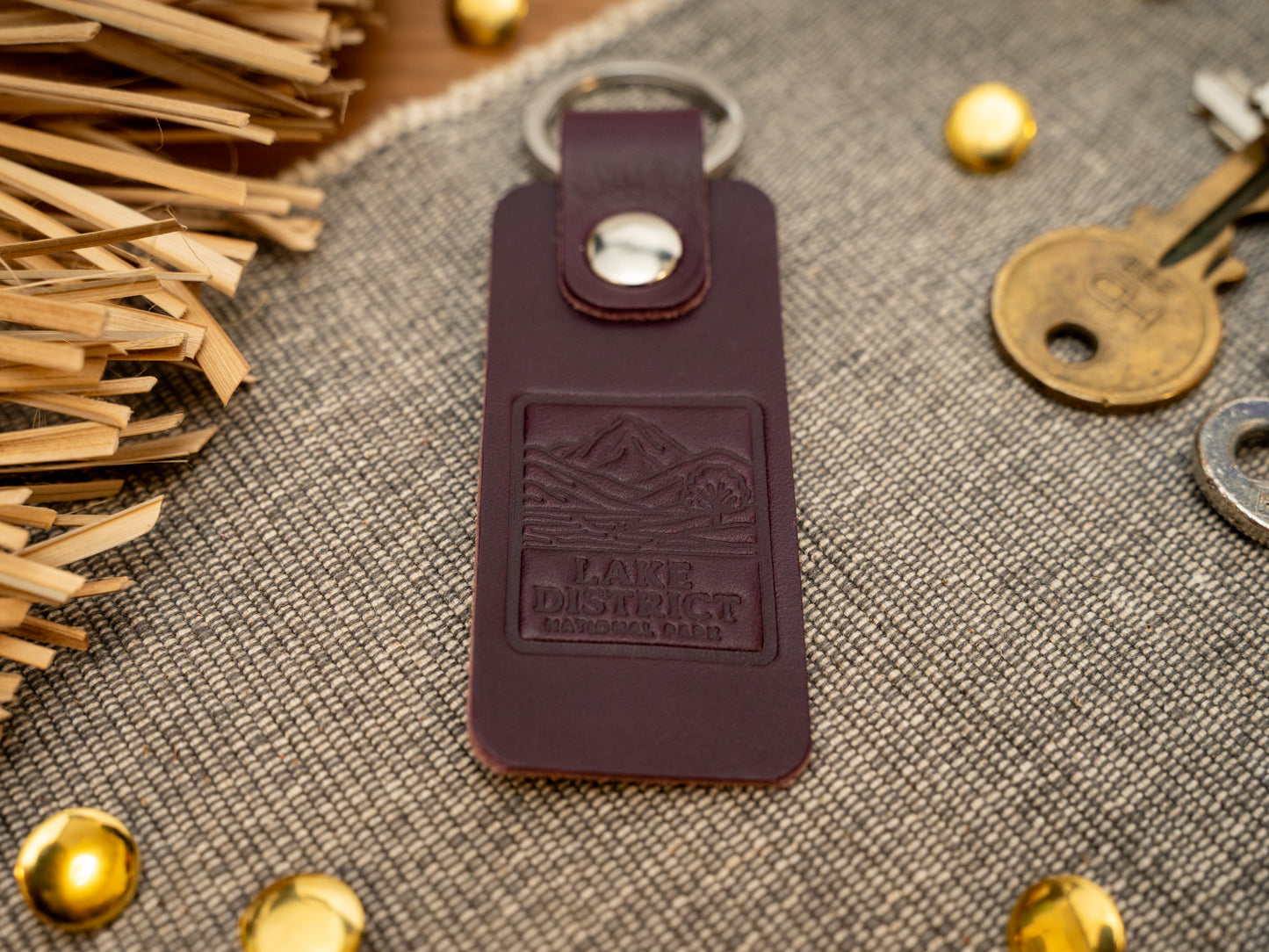 A leather keyring with a rectangular design in purple. Keyring/keychain is debossed with an image of the lake district. Stainless steel split ring and rivet.