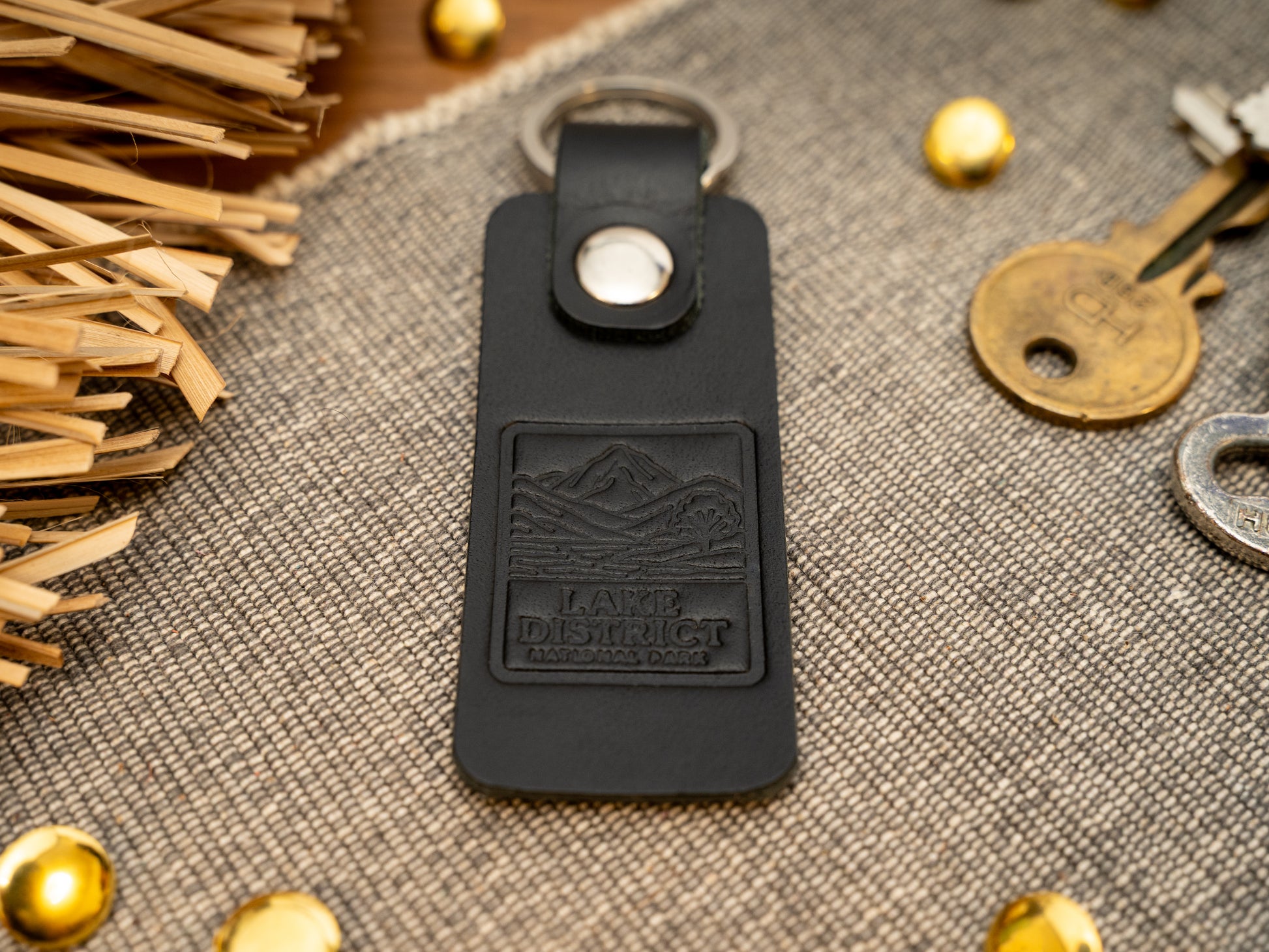 A leather keyring with a rectangular design in black. Keyring/keychain is debossed with an image of the lake district. Stainless steel split ring and rivet.