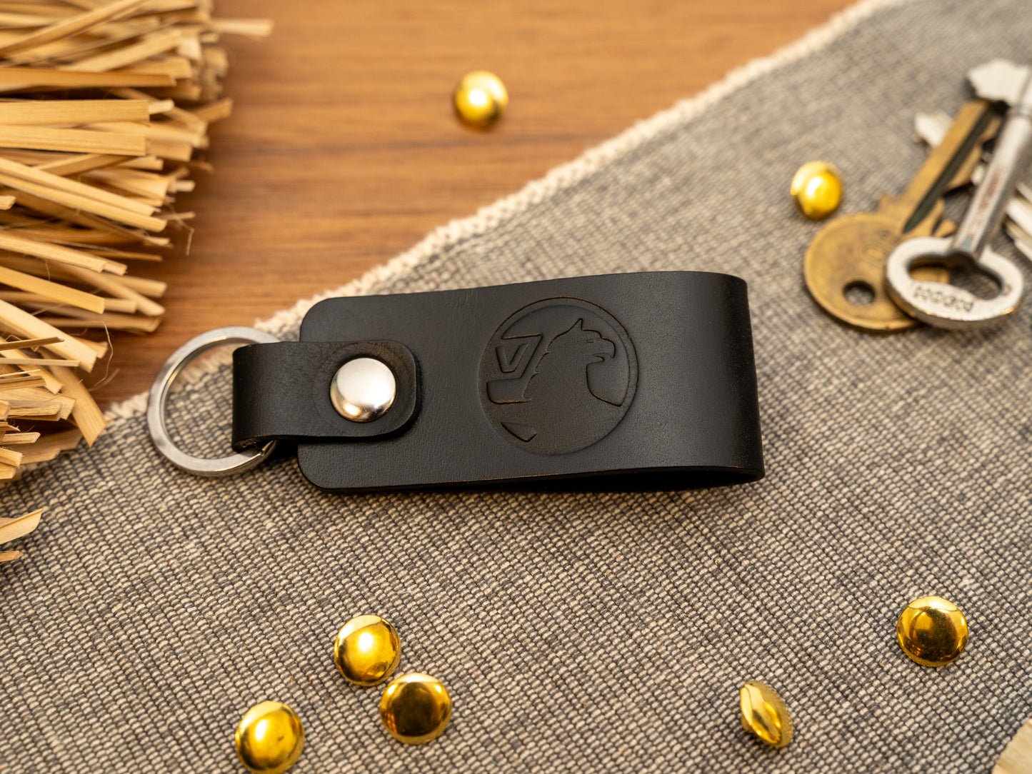 Folded black leather keyring/keychain with the Vauxhall car logo debossed on it. Made from full grain leather with stainless steel split ring and rivet.