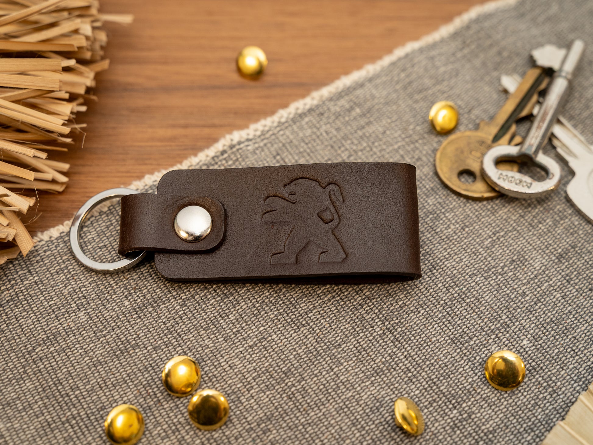 Folded dark brown leather keyring/keychain with the Peugeot car logo debossed on it. Made from full grain leather.