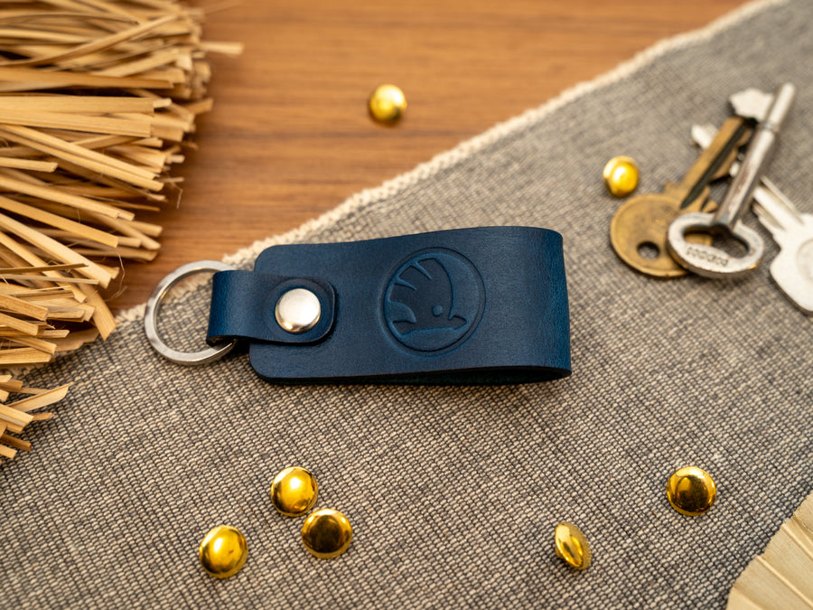 Keyring/keychain with a folded design in navy blue. The keychain has been embossed with the Skoda car logo. Stainless steel split ring and rivet.