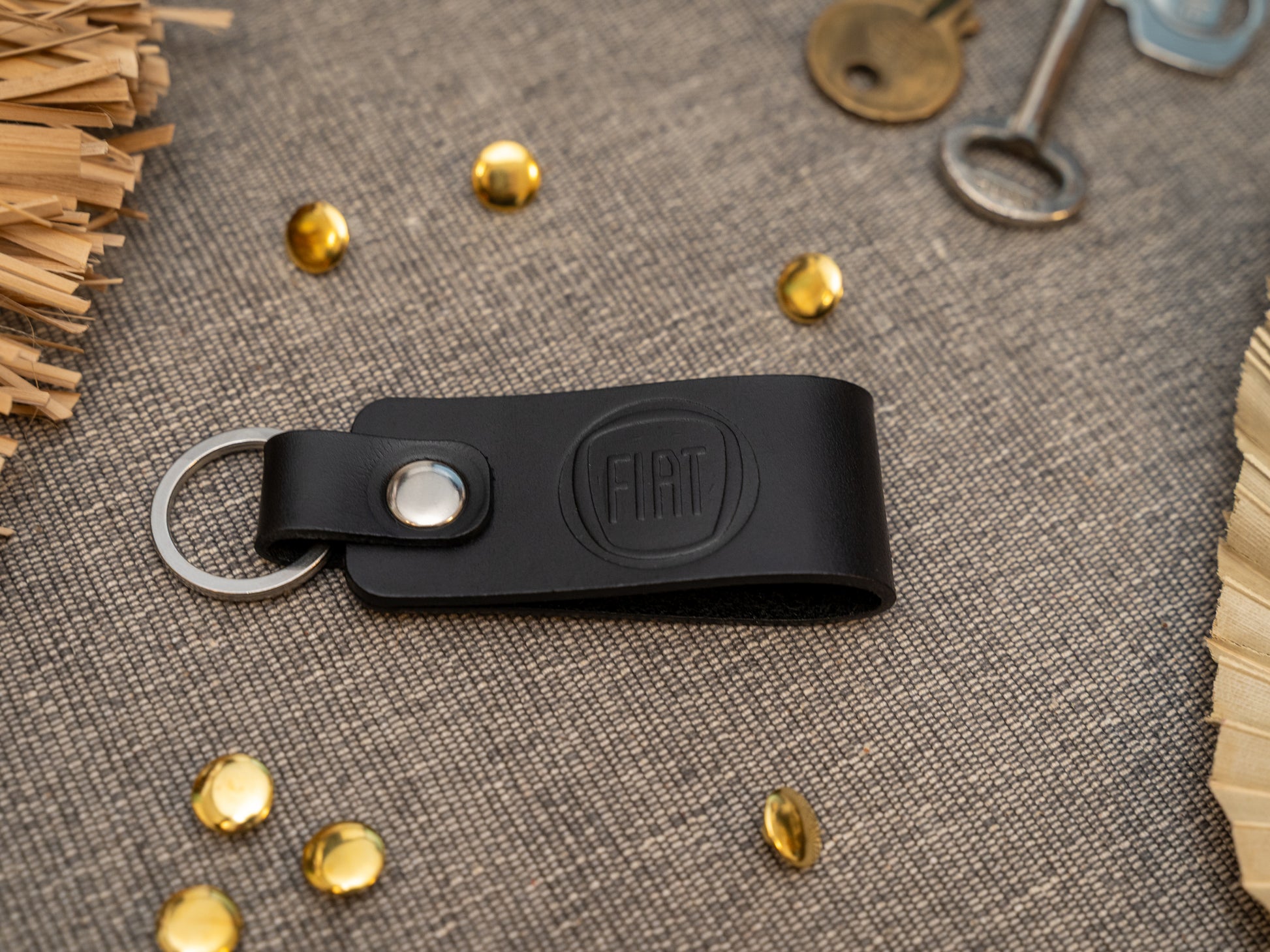 Black leather Fiat car keychain on a textured surface with decorative elements.