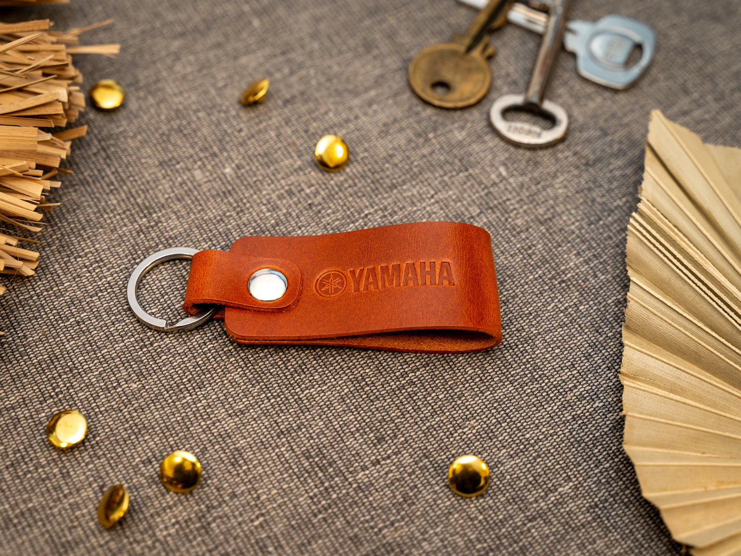 Keyring with a folded design in tan. The keychain has been embossed with the Yamaha motorbike logo. Stainless steel split ring and rivet.