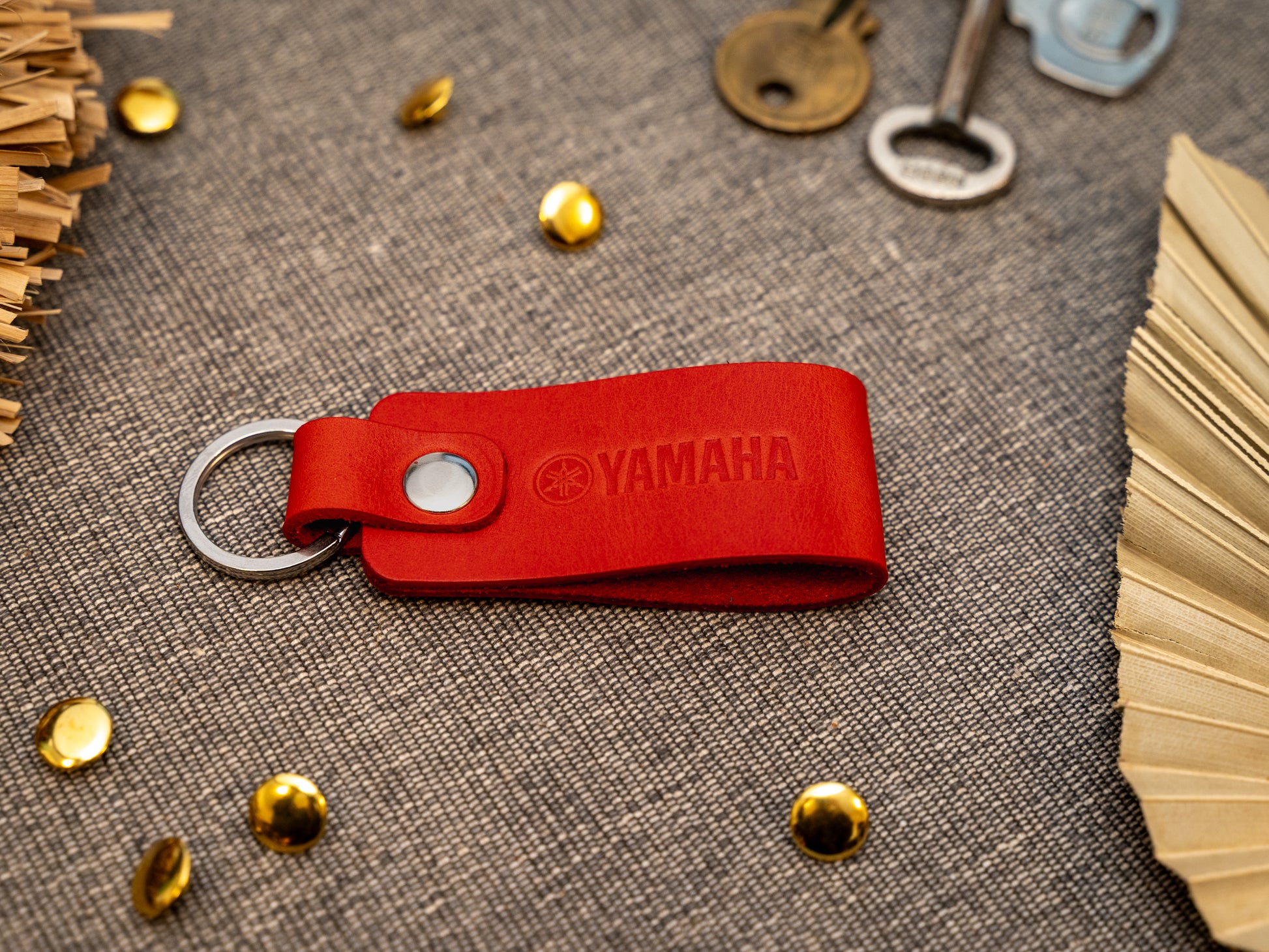Keyring with a folded design in red. The keychain has been embossed with the Yamaha motorbike logo. Stainless steel split ring and rivet.