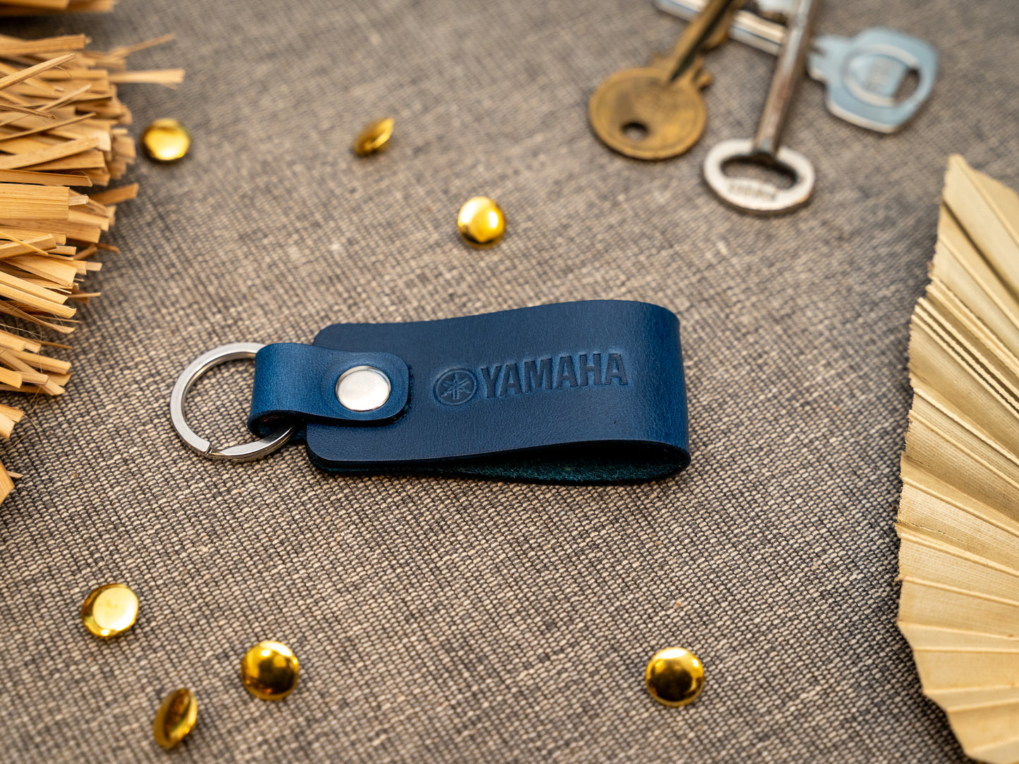 Keyring with a folded design in navy blue. The keychain has been embossed with the Yamaha motorbike logo. Stainless steel split ring and rivet.