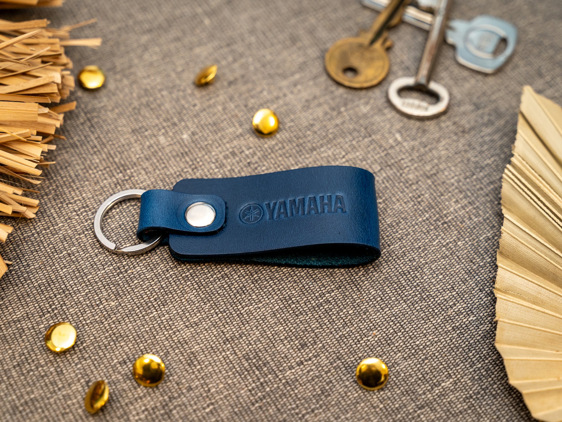Keyring with a folded design in navy blue. The keychain has been embossed with the Yamaha motorbike logo. Stainless steel split ring and rivet.