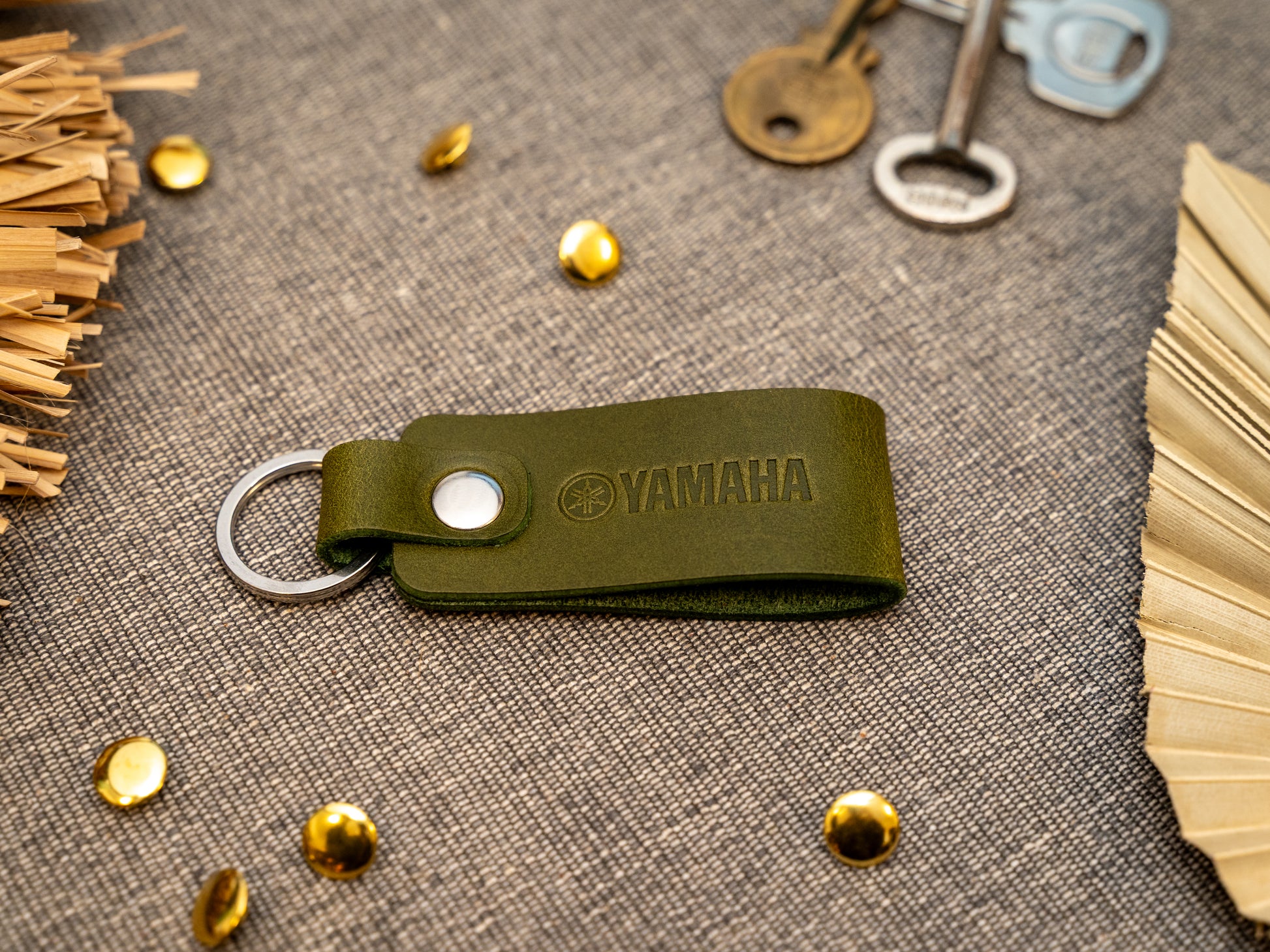 Keyring with a folded design in olive green. The keychain has been embossed with the Yamaha motorbike logo. Stainless steel split ring and rivet.