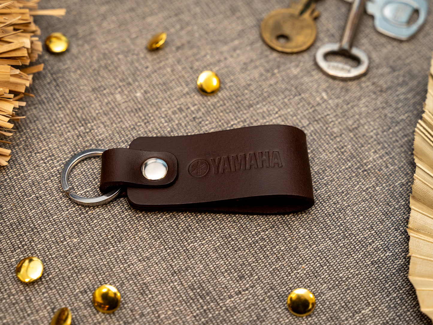 Keyring with a folded design in dark brown. The keychain has been embossed with the Yamaha motorbike logo. Stainless steel split ring and rivet.