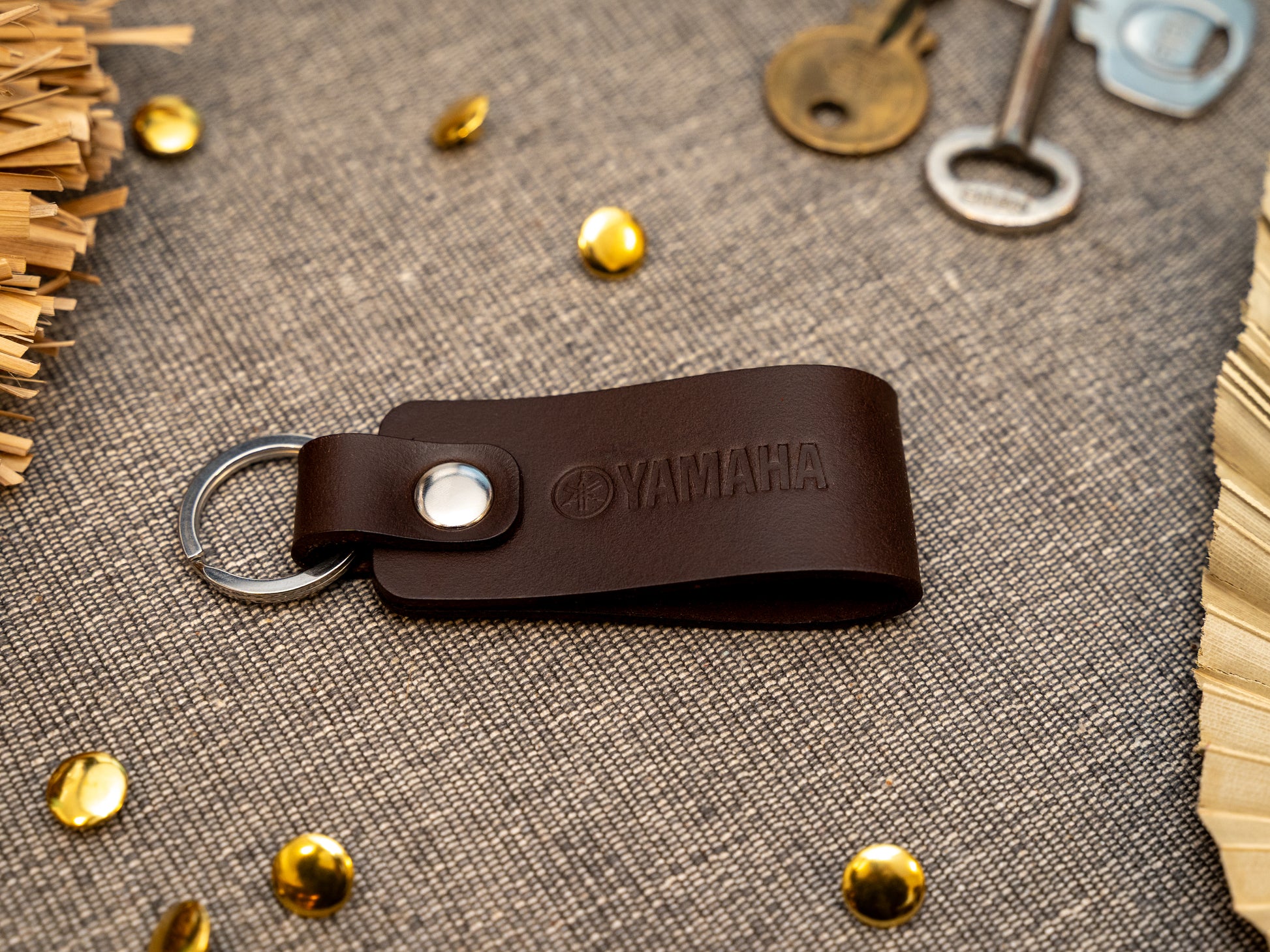 Keyring with a folded design in dark brown. The keychain has been embossed with the Yamaha motorbike logo. Stainless steel split ring and rivet.