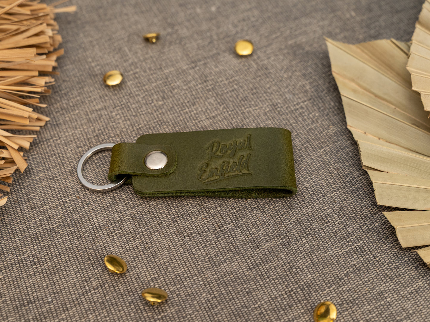 Folded olive green leather keyring/keychain with Royal Enfield in a cursive style font debossed on it. Made from full grain leather with stainless steel split ring and rivet.