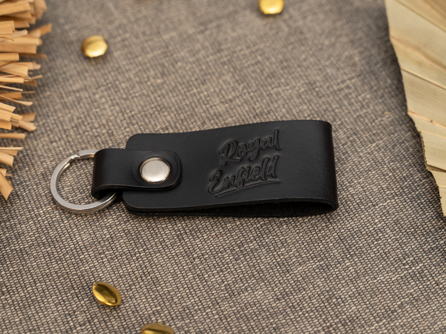 Folded black leather keyring/keychain with Royal Enfield in a cursive style font debossed on it. Made from full grain leather with stainless steel split ring and rivet.