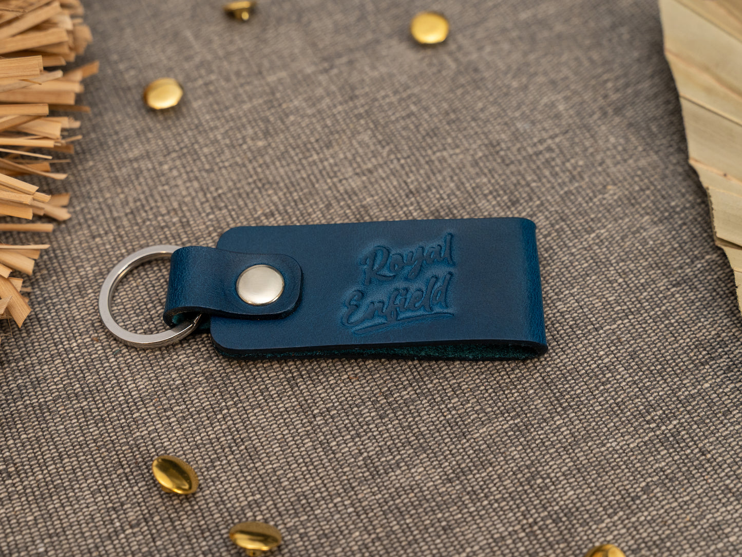 Folded navy blue leather keyring/keychain with Royal Enfield in a cursive style font debossed on it. Made from full grain leather with stainless steel split ring and rivet.