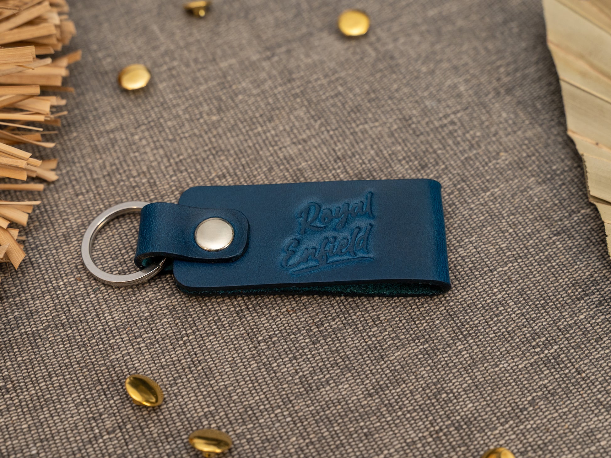 Folded navy blue leather keyring/keychain with Royal Enfield in a cursive style font debossed on it. Made from full grain leather with stainless steel split ring and rivet.