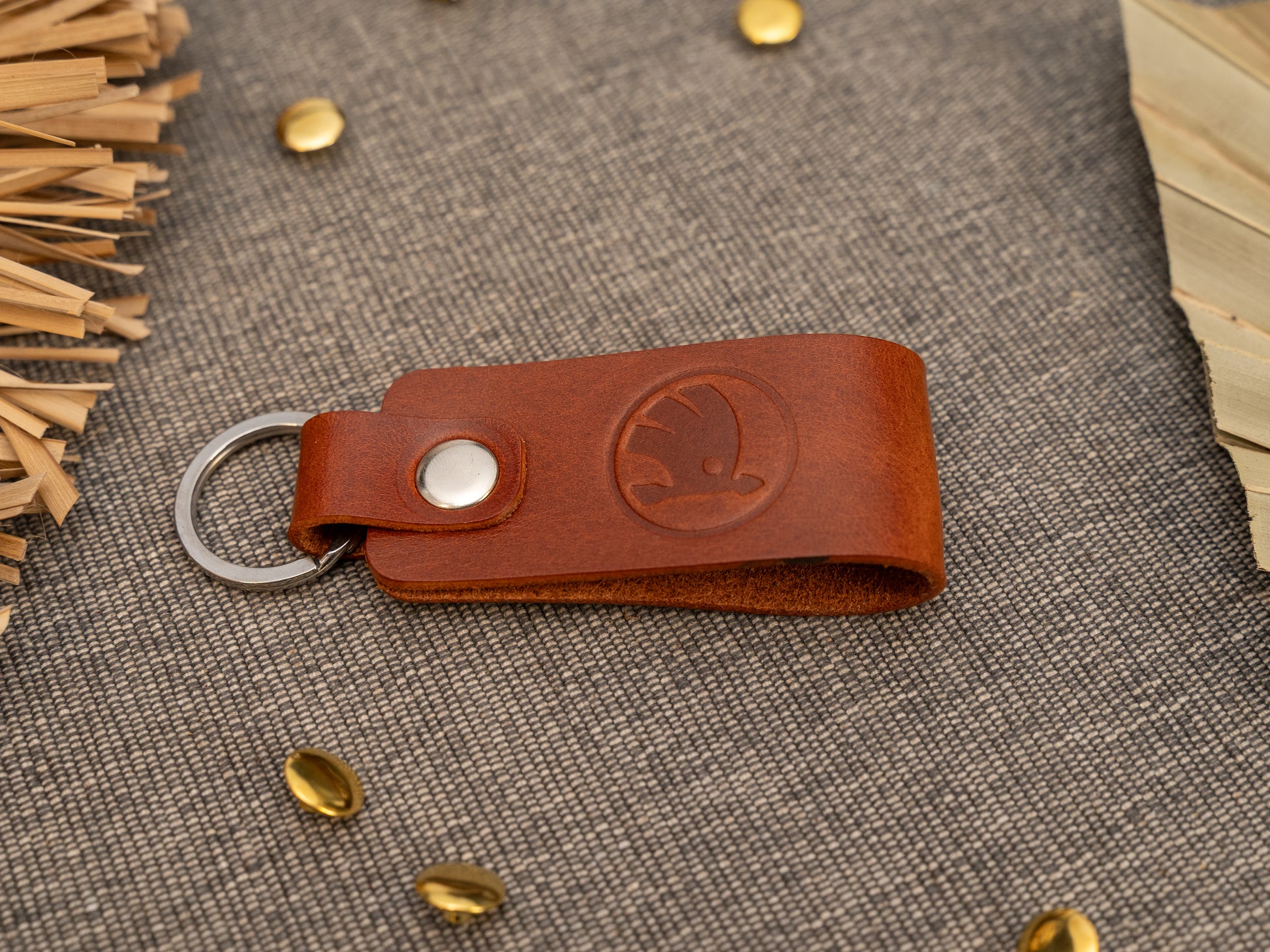 Keyrings with a folded design in tan. The keychain has been embossed with the Skoda car logo. Stainless steel split ring and rivet.