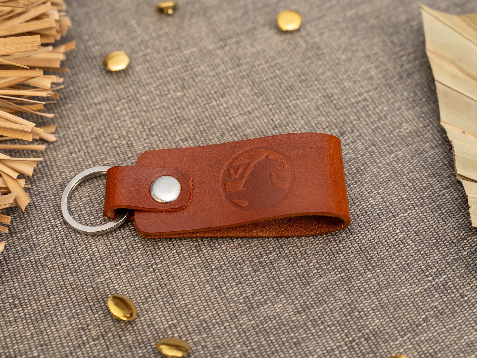 Folded tan leather keyring/keychain with the Vauxhall car logo debossed on it. Made from full grain leather with stainless steel split ring and rivet.