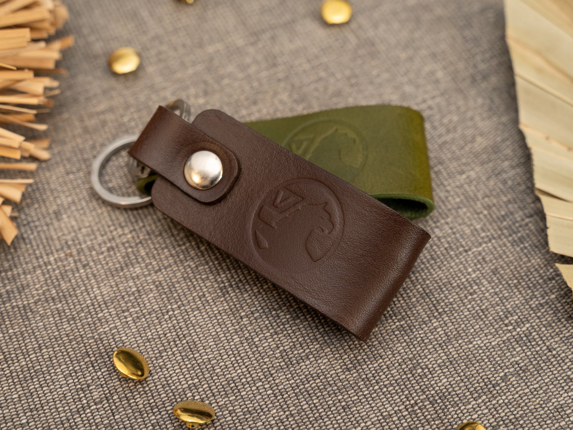 Folded dark brown and olive green leather keyrings/keychains with the Vauxhall car logo debossed on them. Made from full grain leather with stainless steel split ring and rivet.