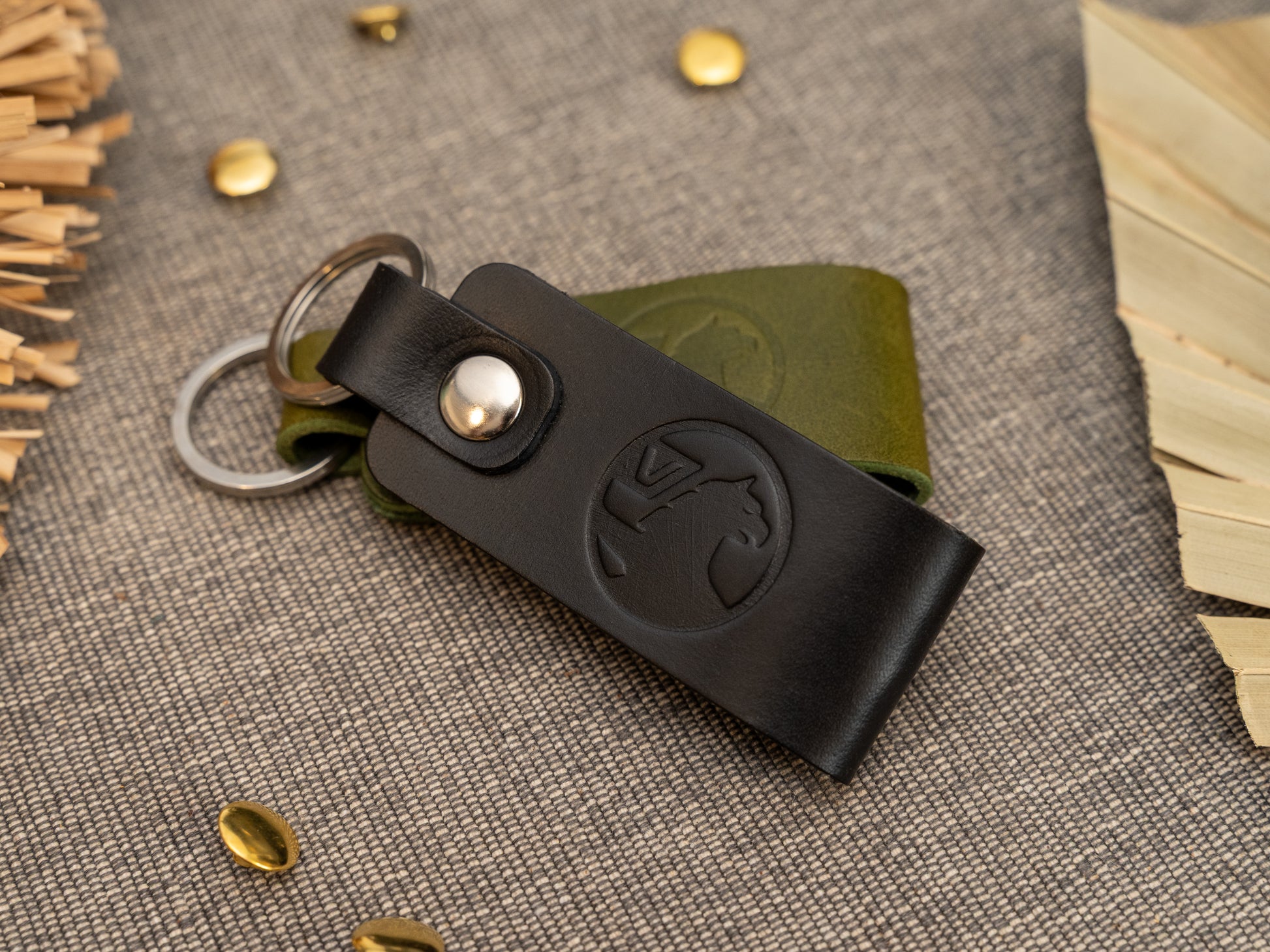 Folded black and olive green leather keyrings/keychains with the Vauxhall car logo debossed on them. Made from full grain leather with stainless steel split ring and rivet.